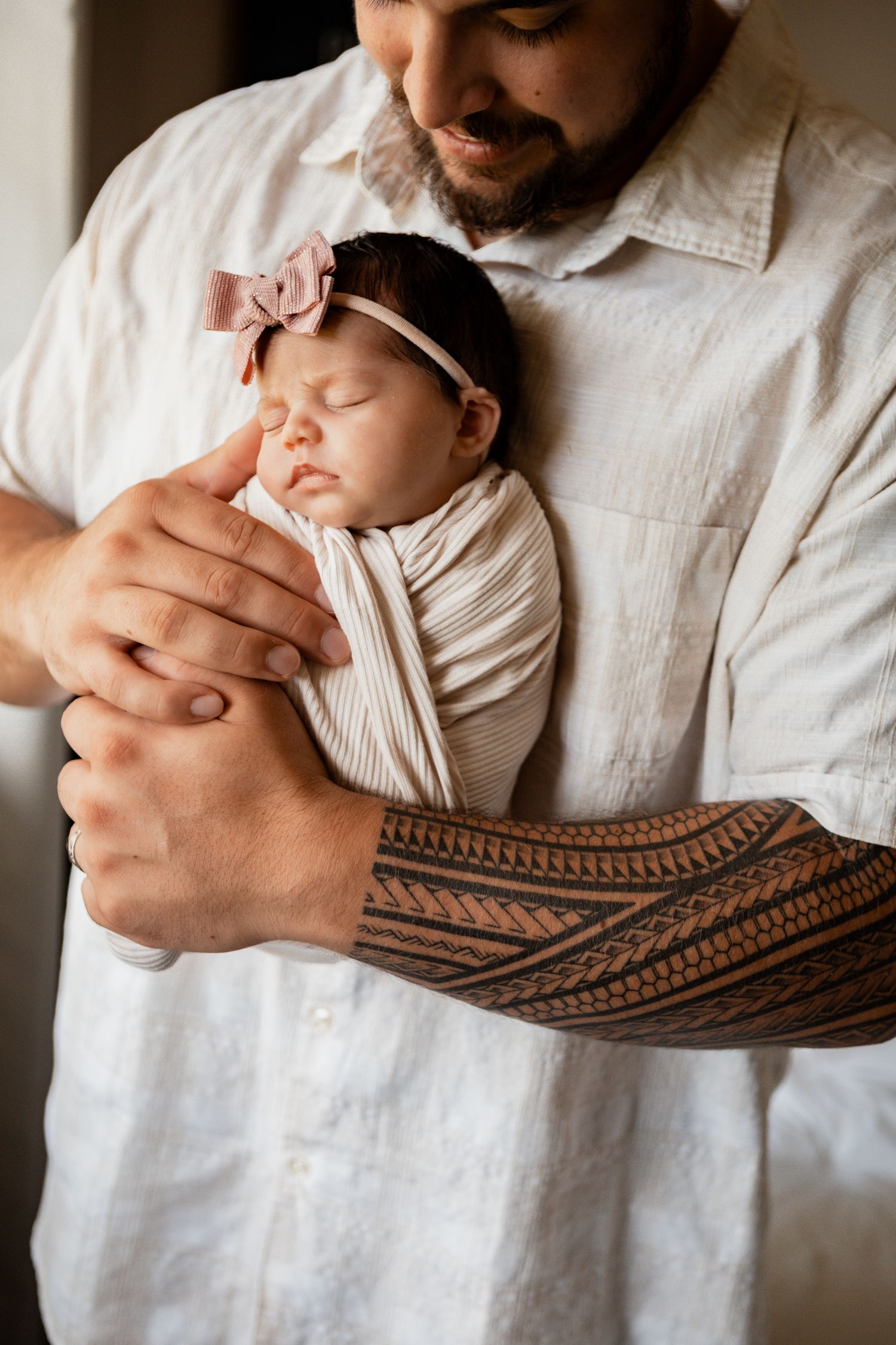 A parent in a white shirt holds a sleeping baby in a knitted brown hammock in a series of close-up shots.