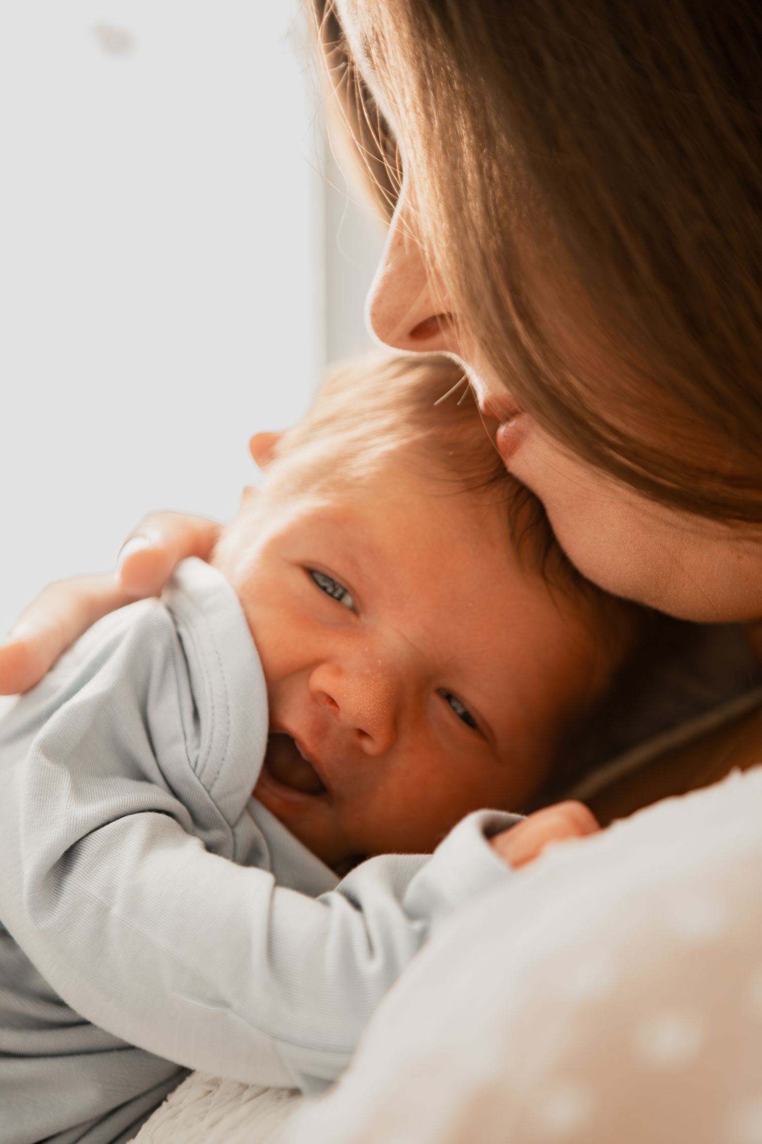 A tender moment between parent and infant in soft natural light.