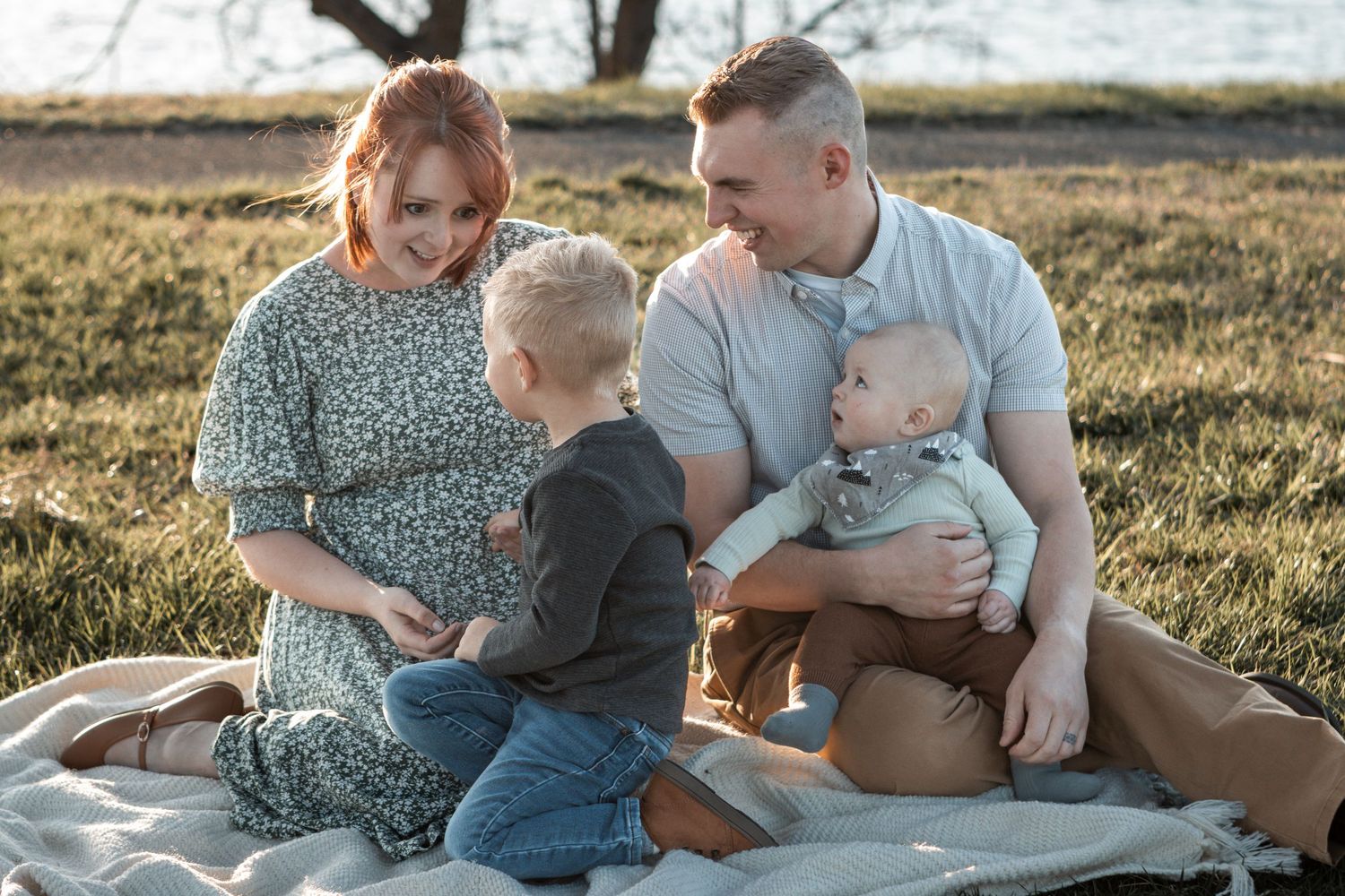 Family spending quality time together while sitting on a picnic blanket during a golden hour photo session.