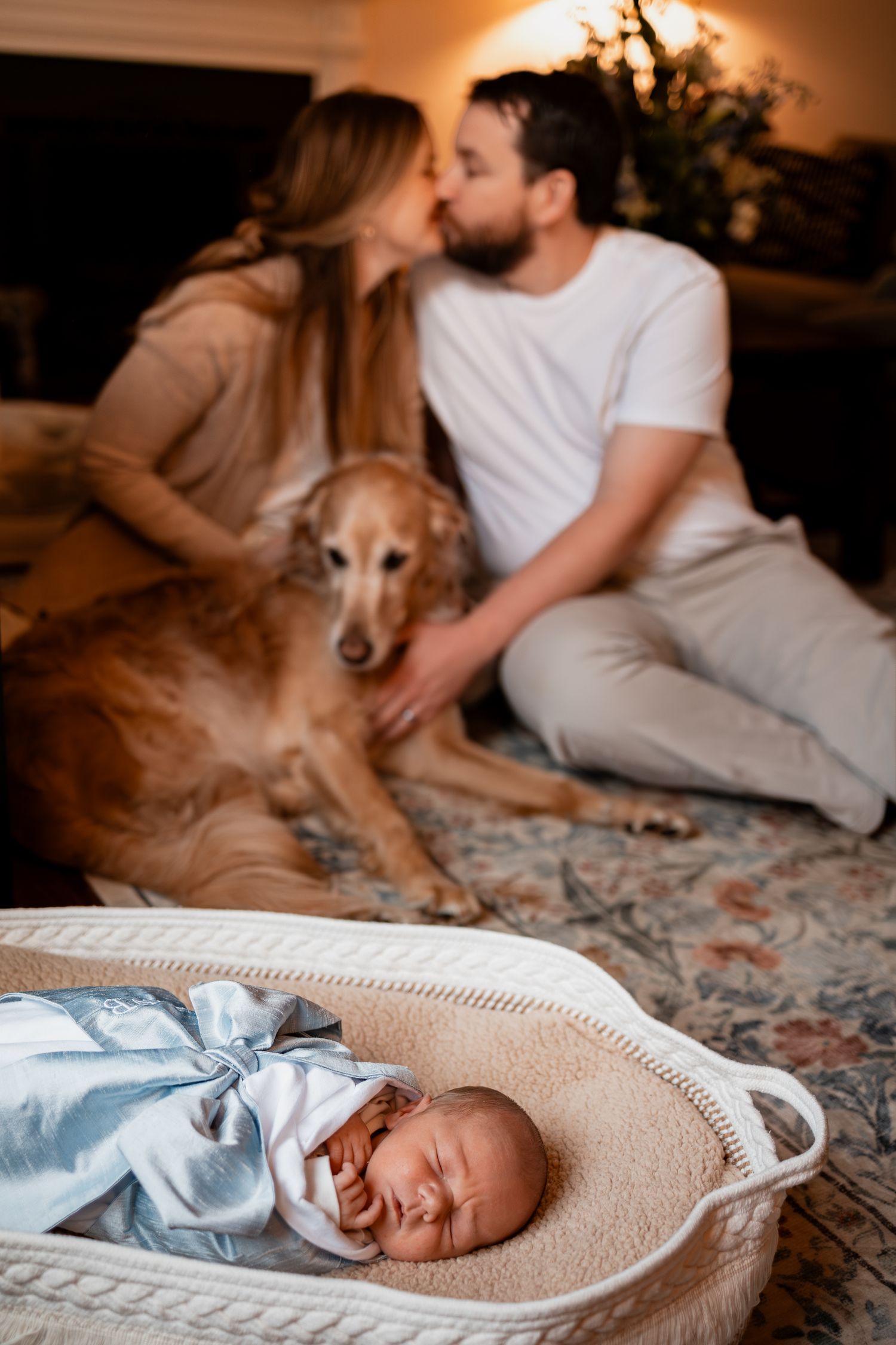Newborn sleeping peacefully in beige swaddle next to dog on floral bedding.
