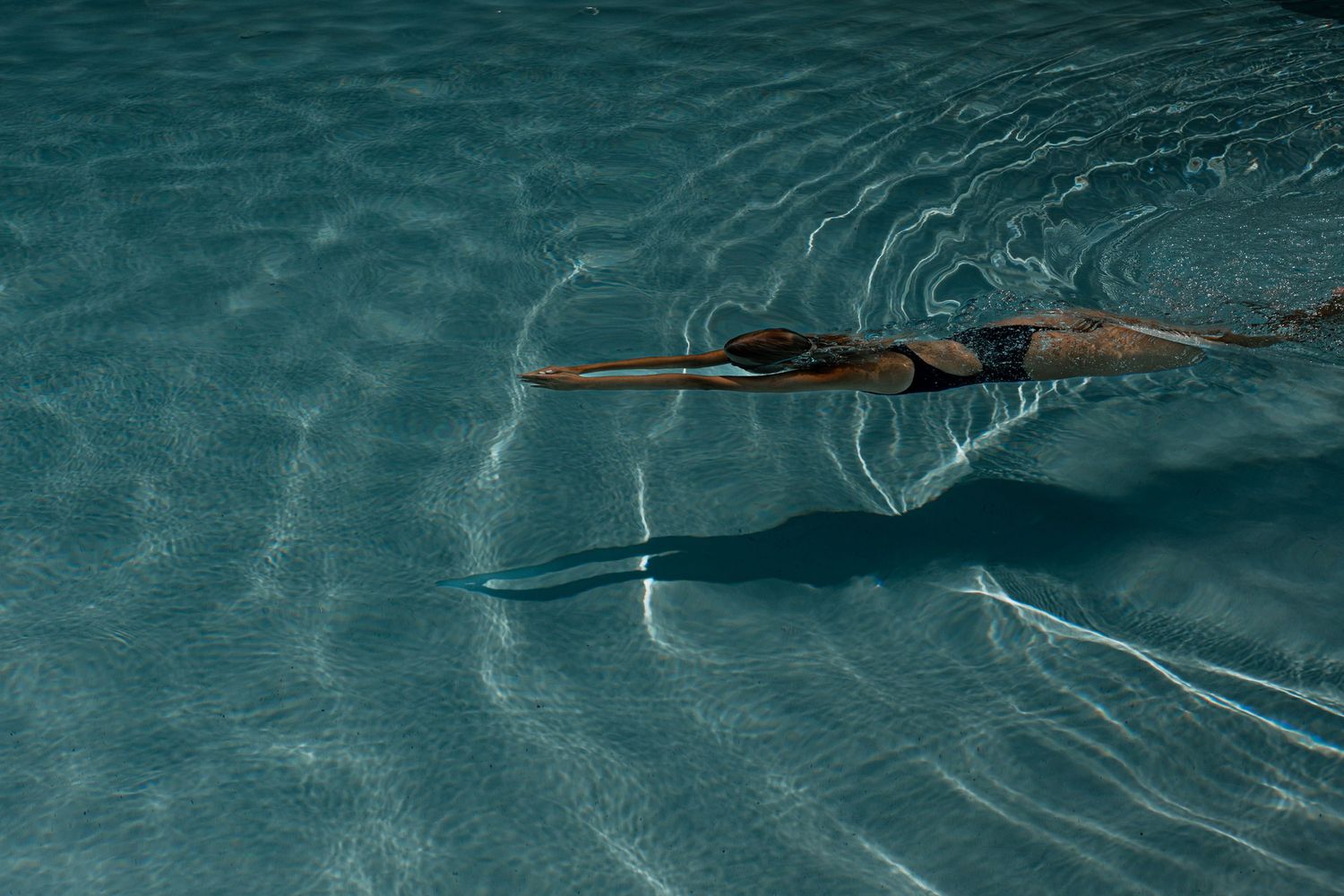 Rippling turquoise pool water surface creates abstract patterns and reflections.