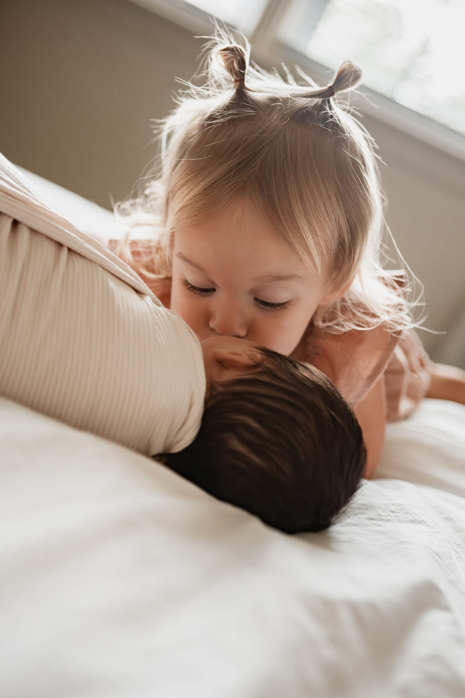 A child lies on a white pillow in soft, natural light while resting their head.