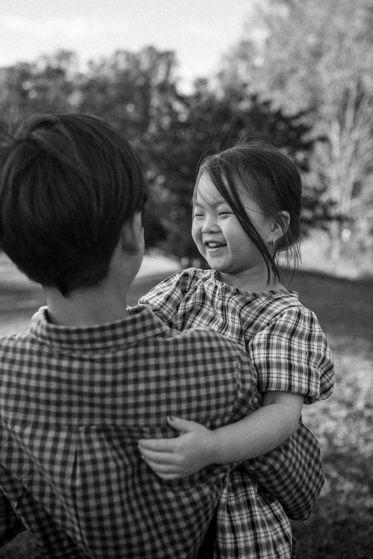 A series of black and white photos showing two people in plaid shirts hugging and laughing together outdoors.
