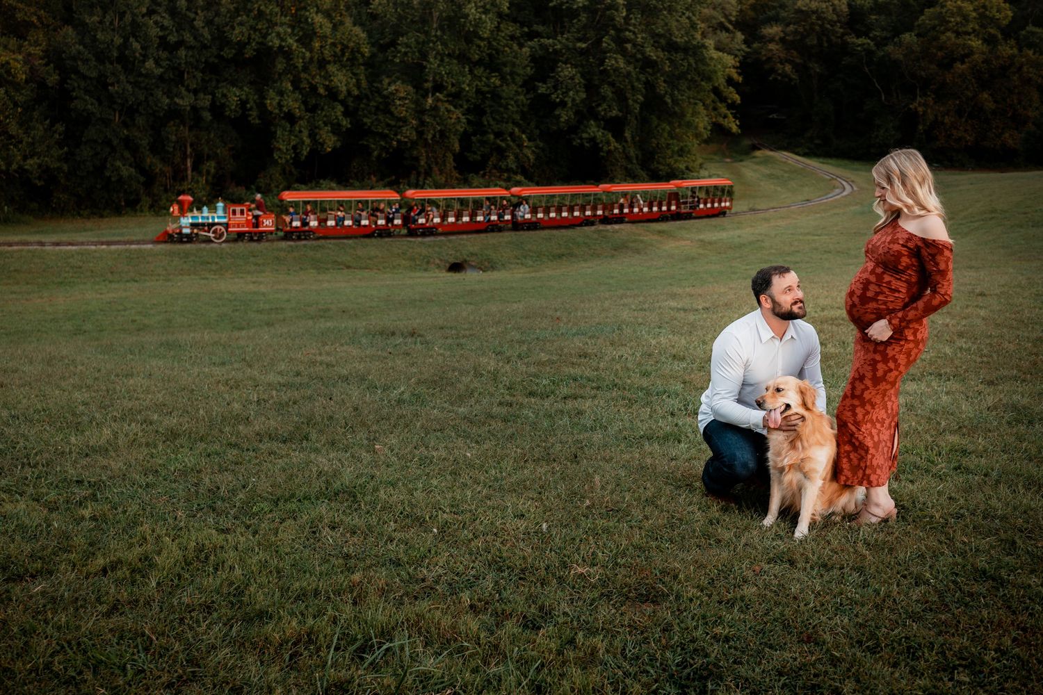 A panoramic view of a couple and their dog in a park during autumn.