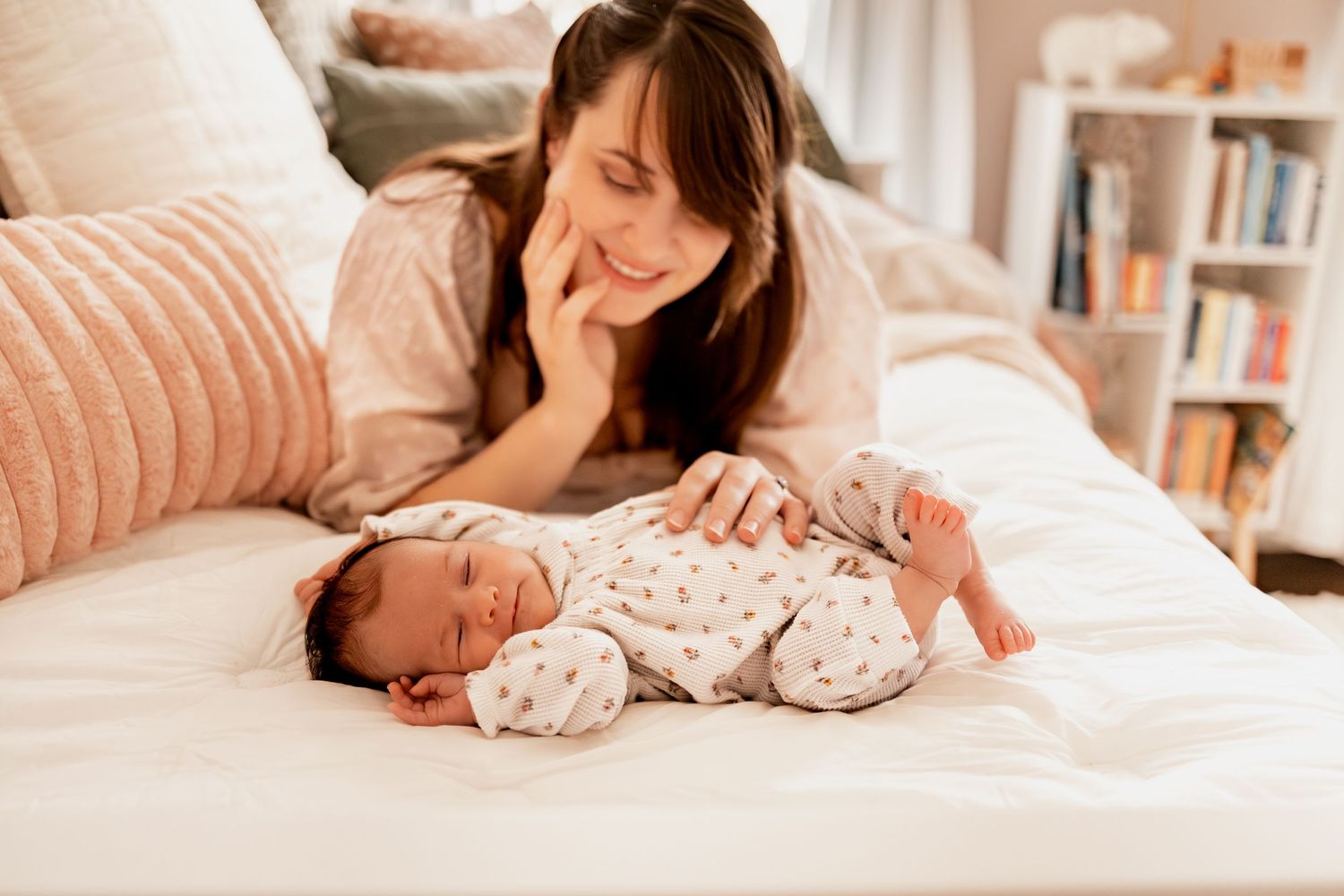 Tender moments between parent and newborn baby in soft natural light on white bedding.