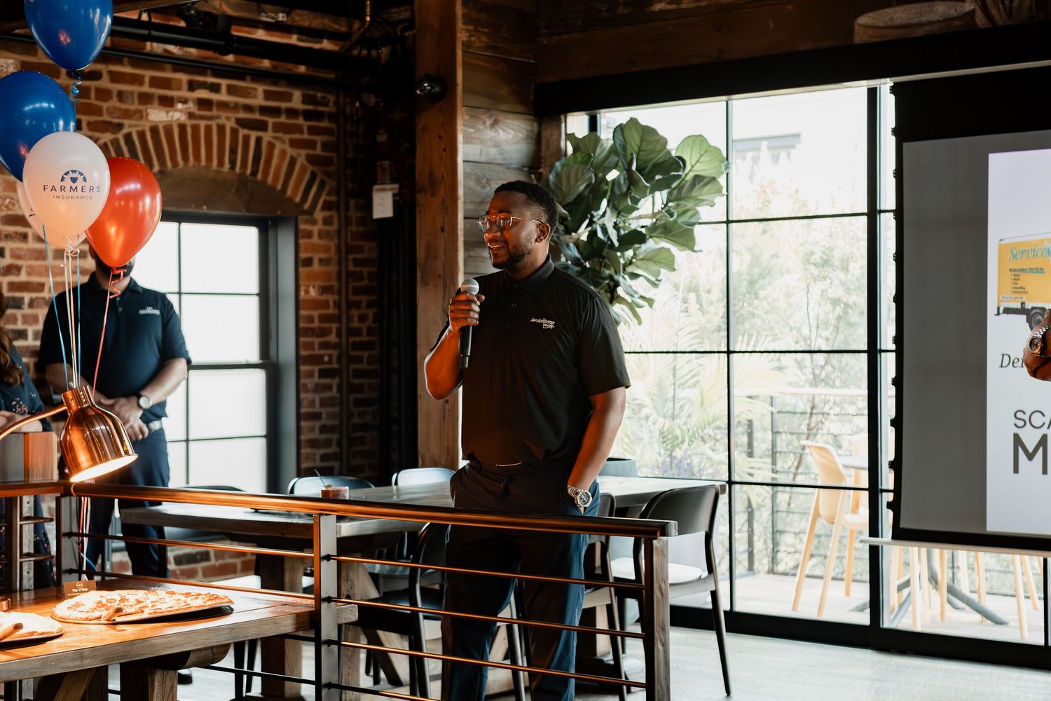 Interior of modern coffee shop with barista workstation at wooden counter and rustic exposed brick walls.