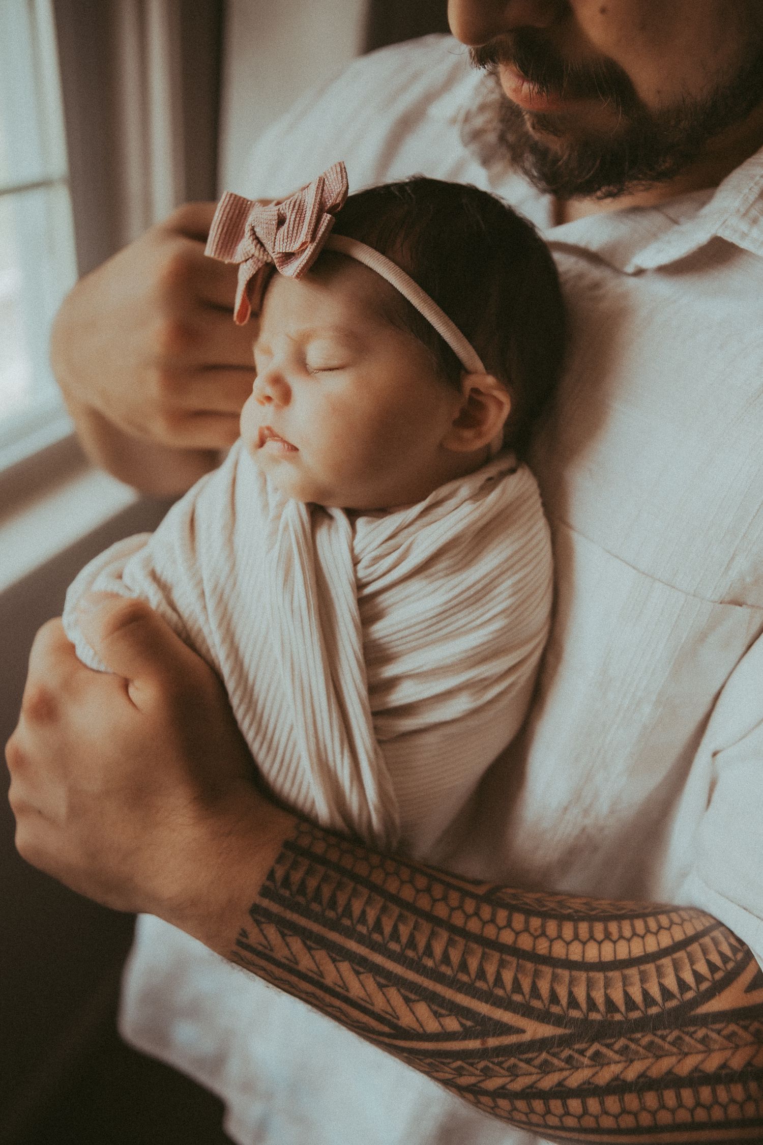 A series of intimate close-up shots showing a sleeping baby resting on someone wearing a tribal tattoo pattern.