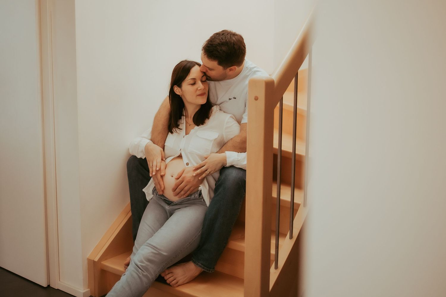 Couple sitting on wooden stairs in a cozy indoor setting sharing intimate moments together.