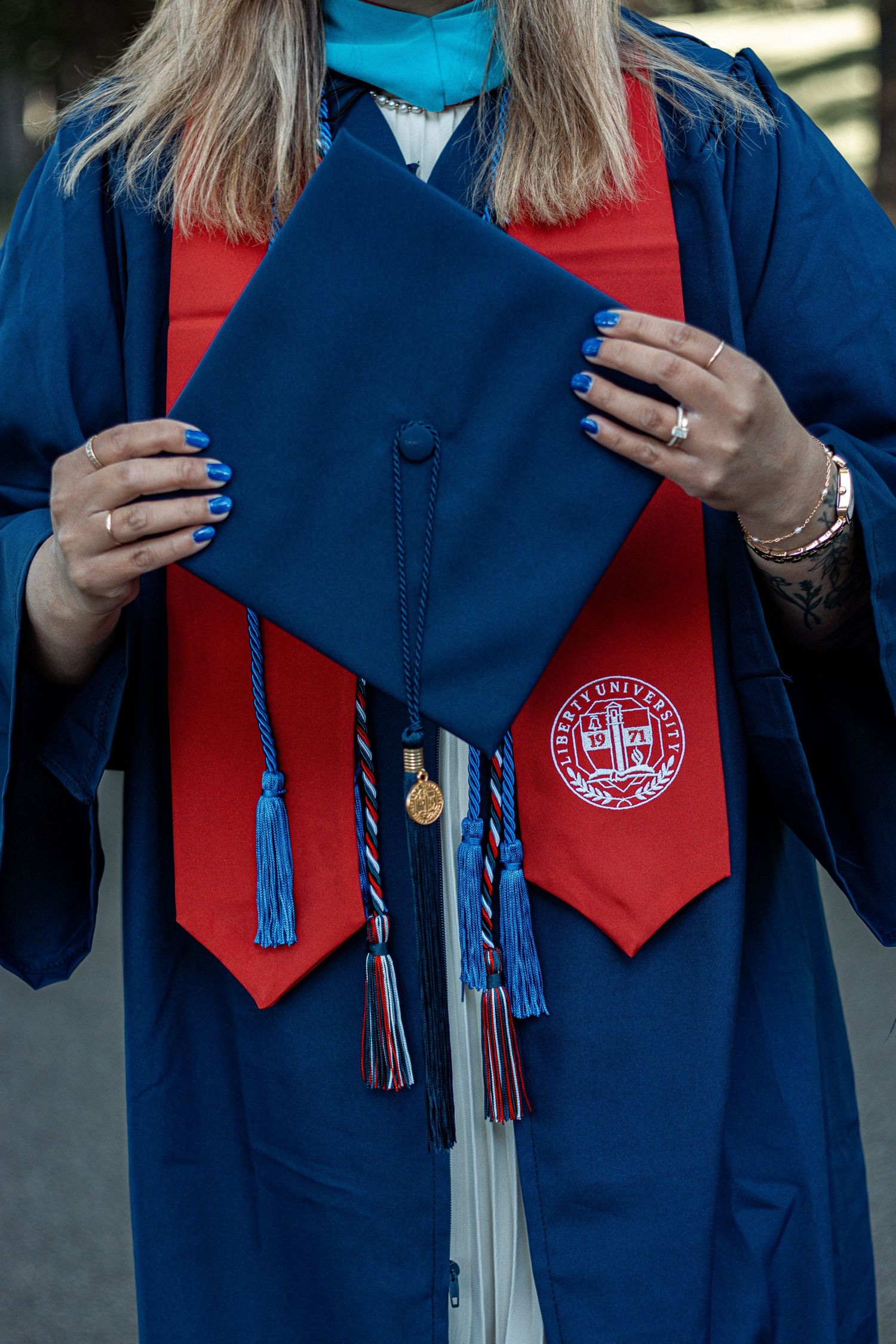 Close-up detail of graduation regalia showing school emblem, honor cords and stole.