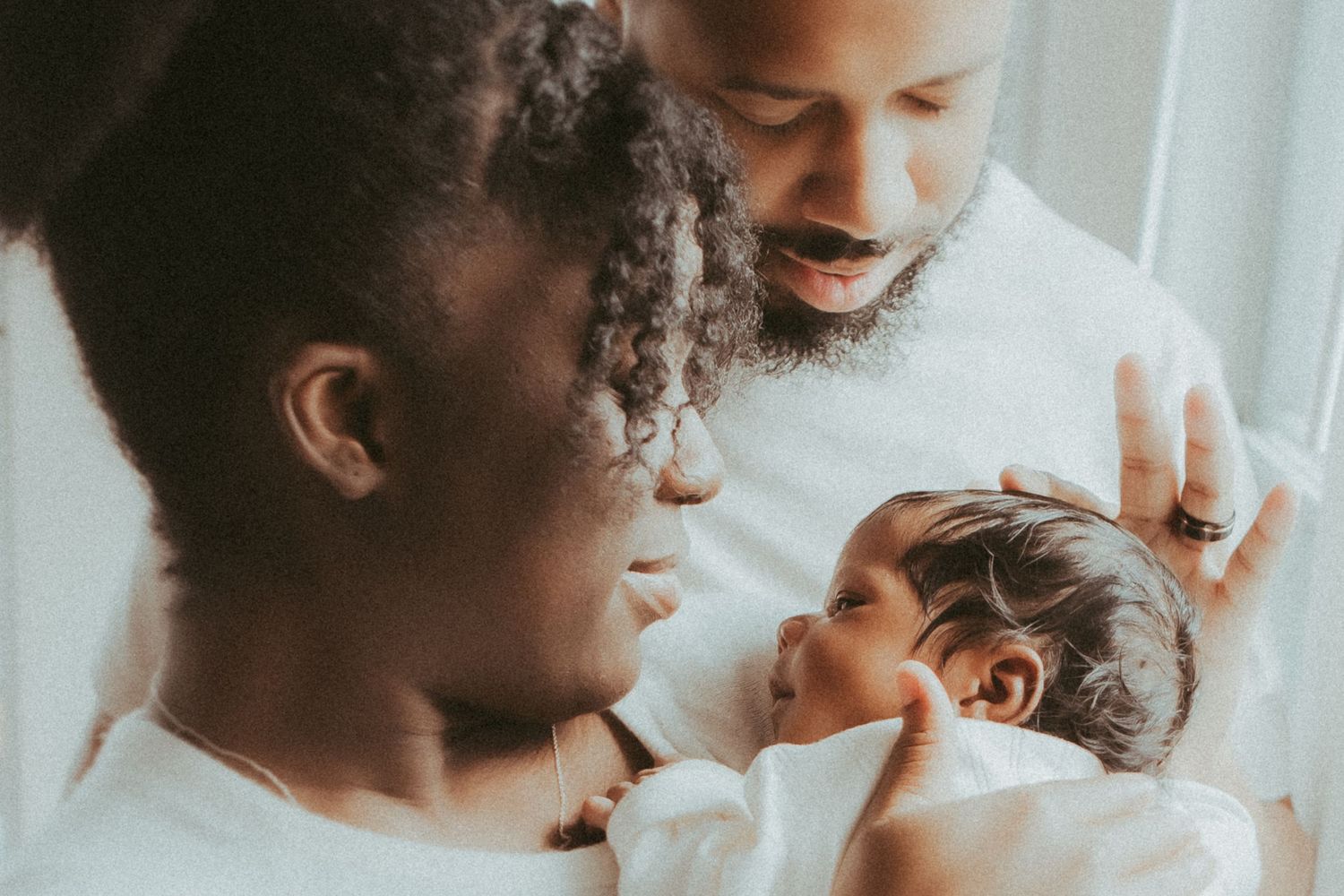 A series of intimate black and white photos showing tender moments between a parent and newborn baby.