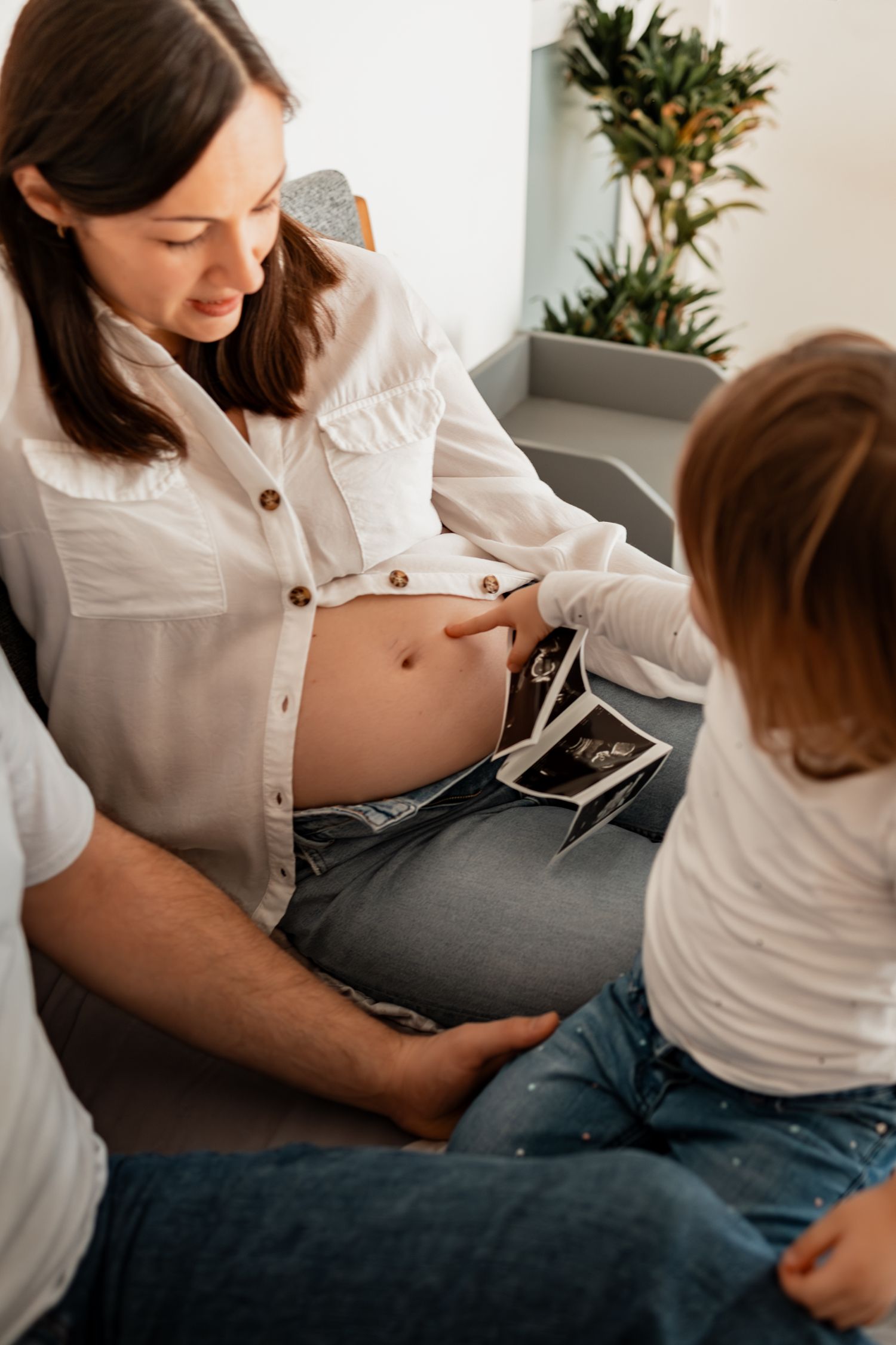 Parent and child sharing a tender moment while looking at a digital device on a couch.