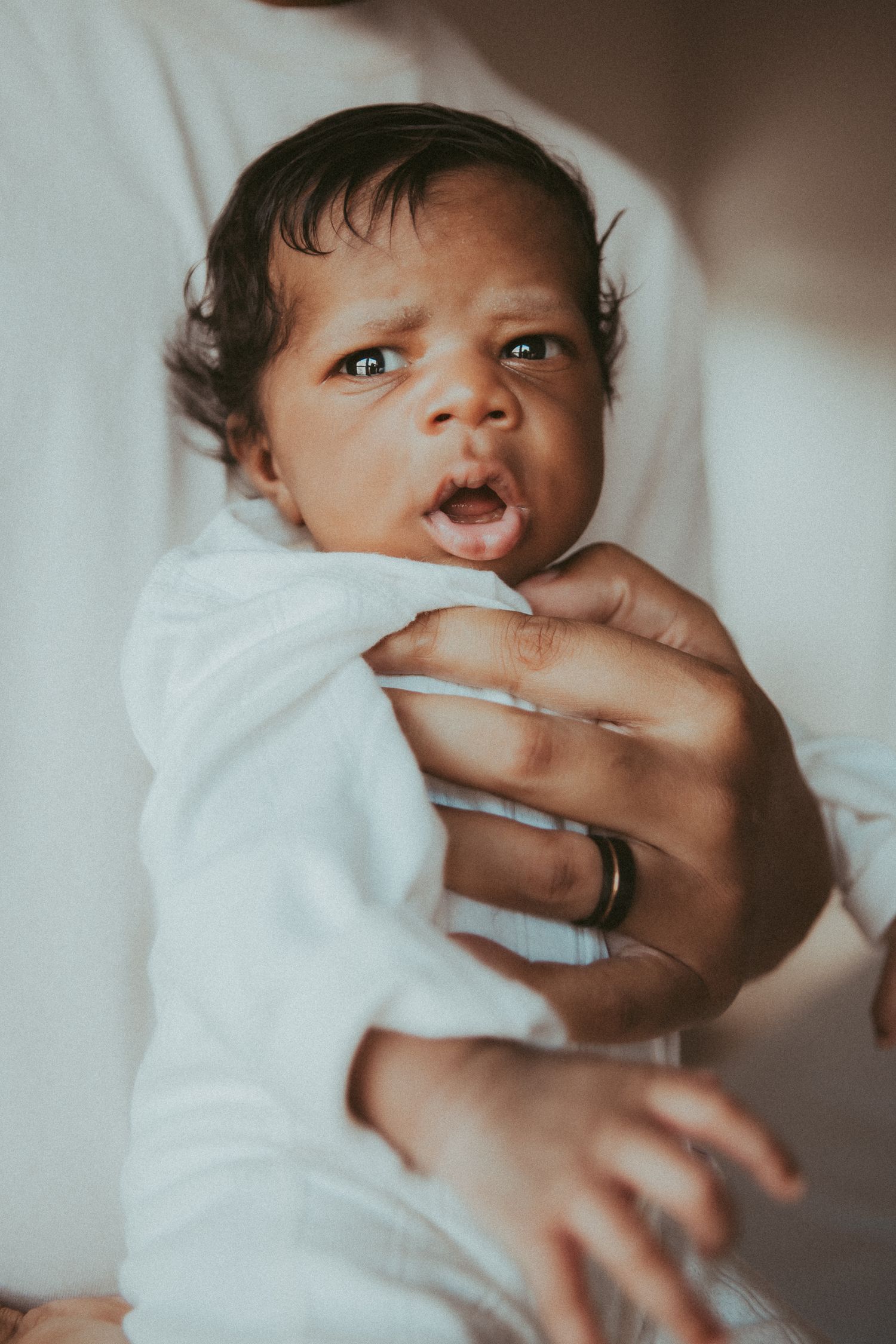 A newborn baby wrapped in white blankets is shown in a series of peaceful sleeping poses.