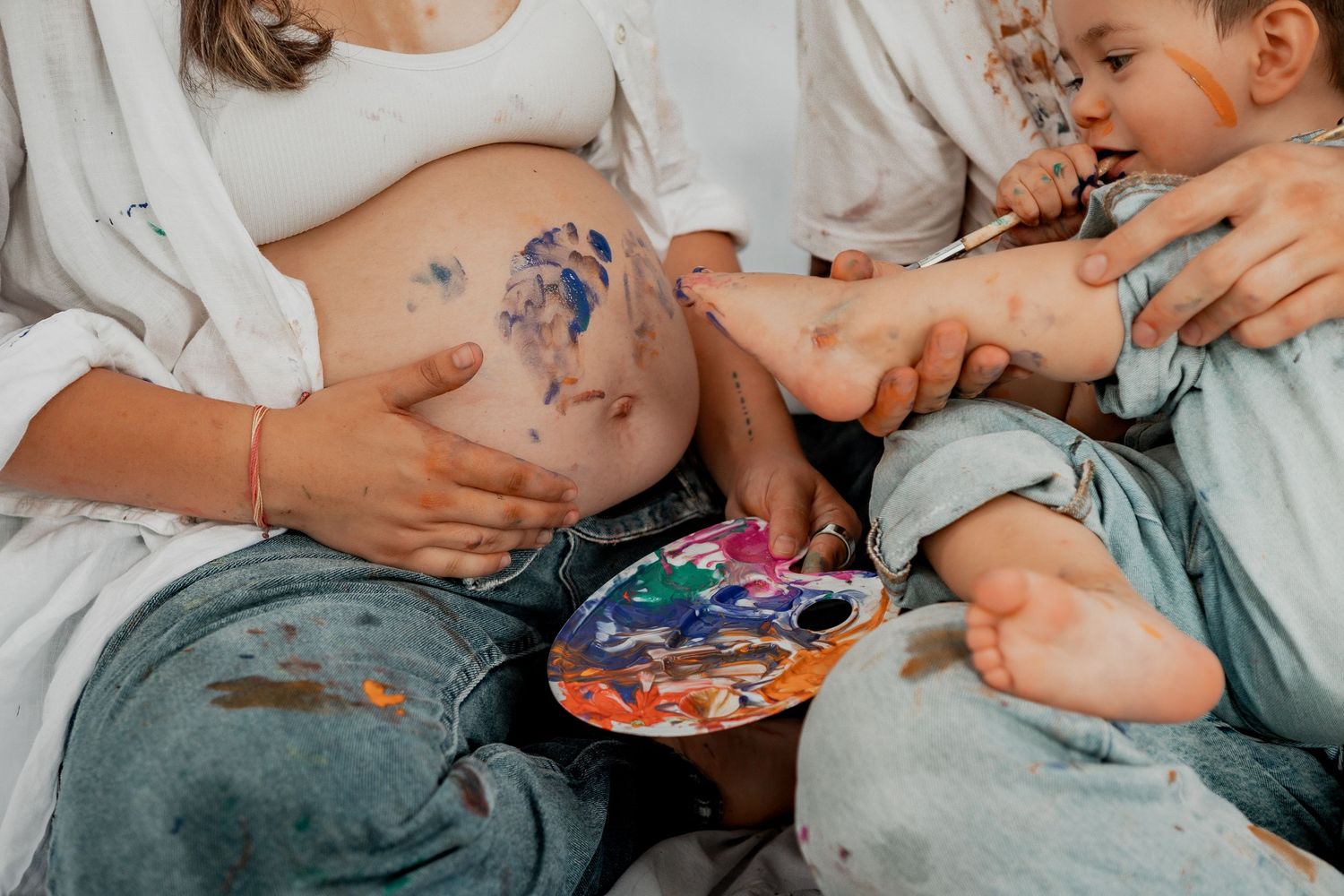 Sweet couple kissing while sitting and painting together in a playful romantic moment.