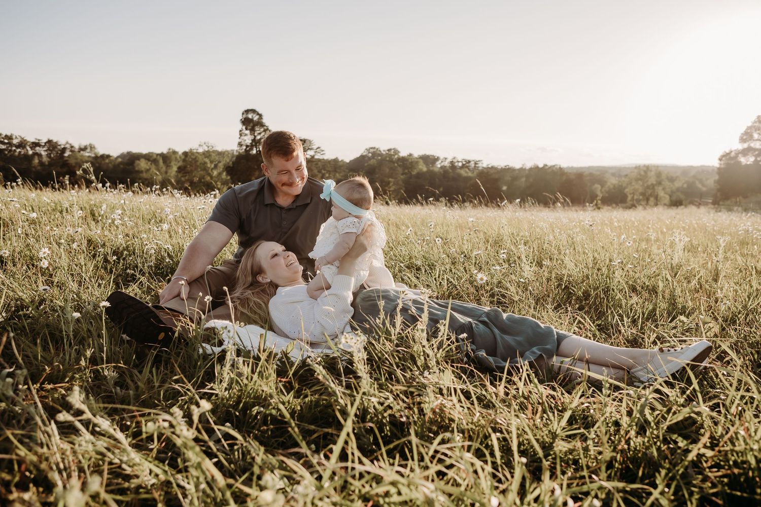 Happy couple in elegant wedding attire embraces in golden sunset field creating romantic outdoor portraits.