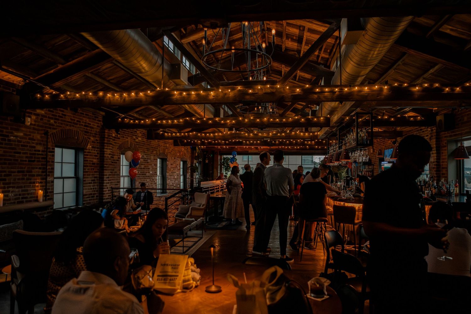 A series of dark and atmospheric rustic barn wedding reception venues decorated with warm string lights and elegant decor.