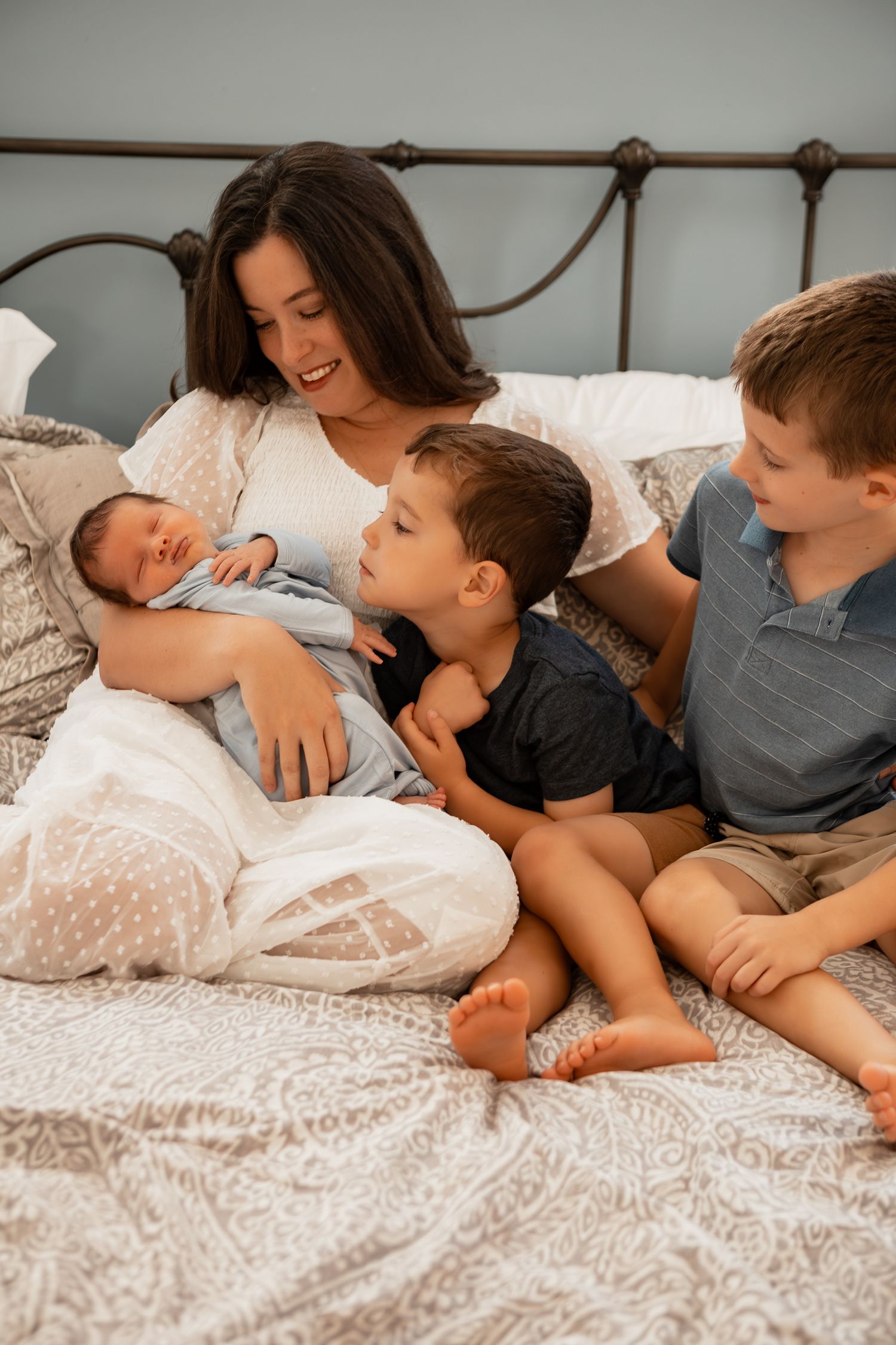 Family sharing tender moments together while relaxing on a bed with white bedding and blankets.