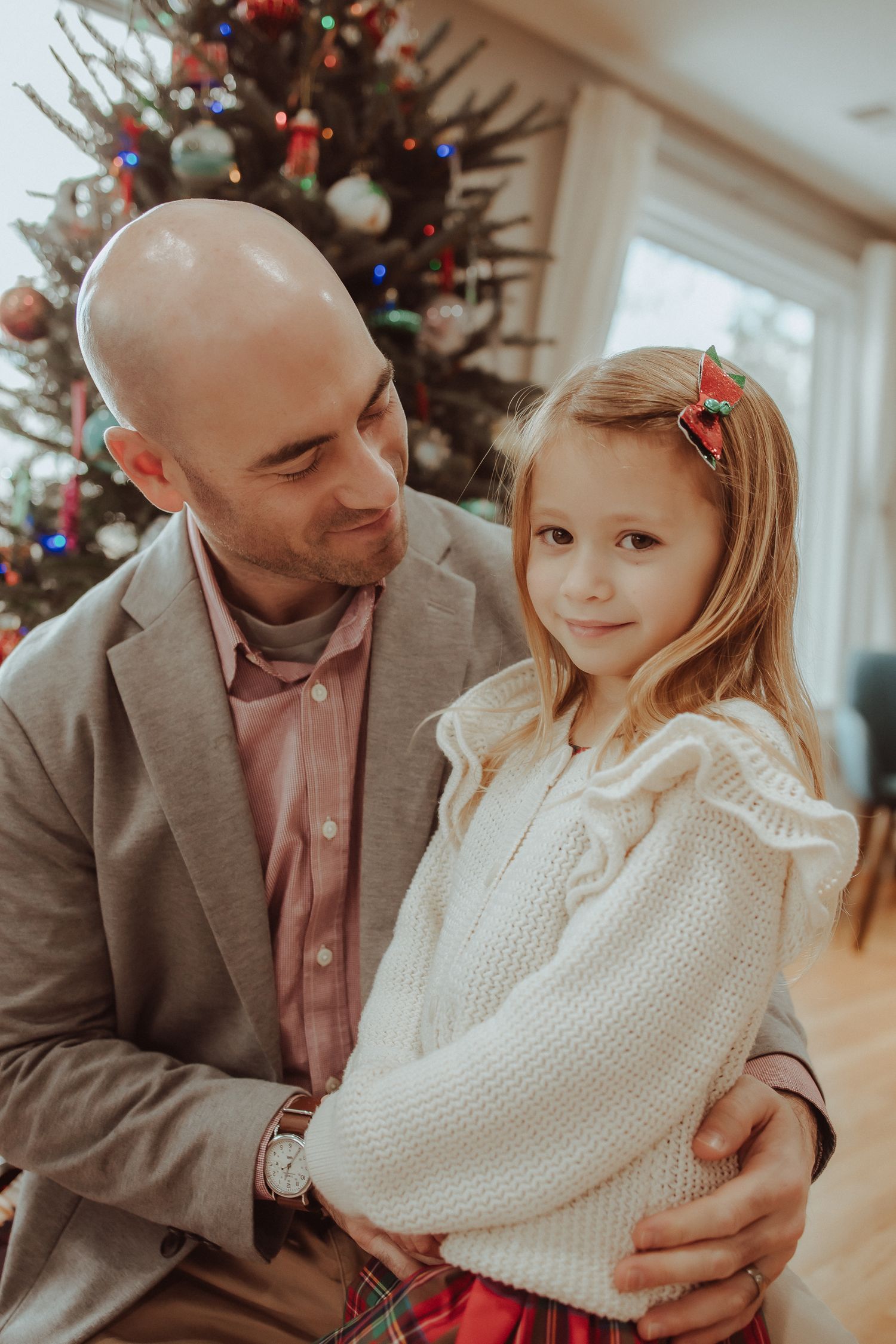 A series of tender holiday moments between a parent and child in front of a decorated Christmas tree.