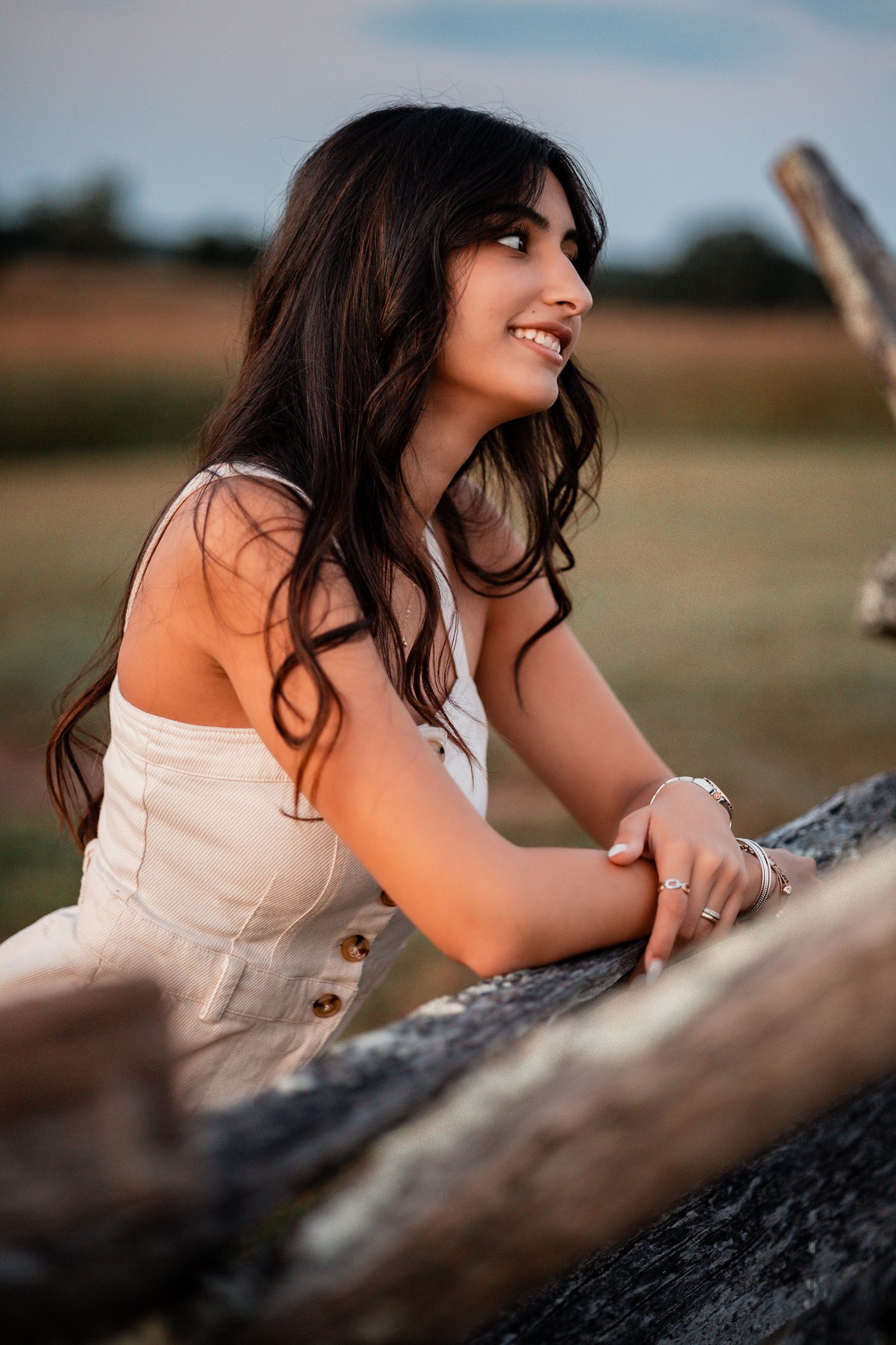 Soft portrait shot at sunset with warm lighting and natural outdoor scenery.