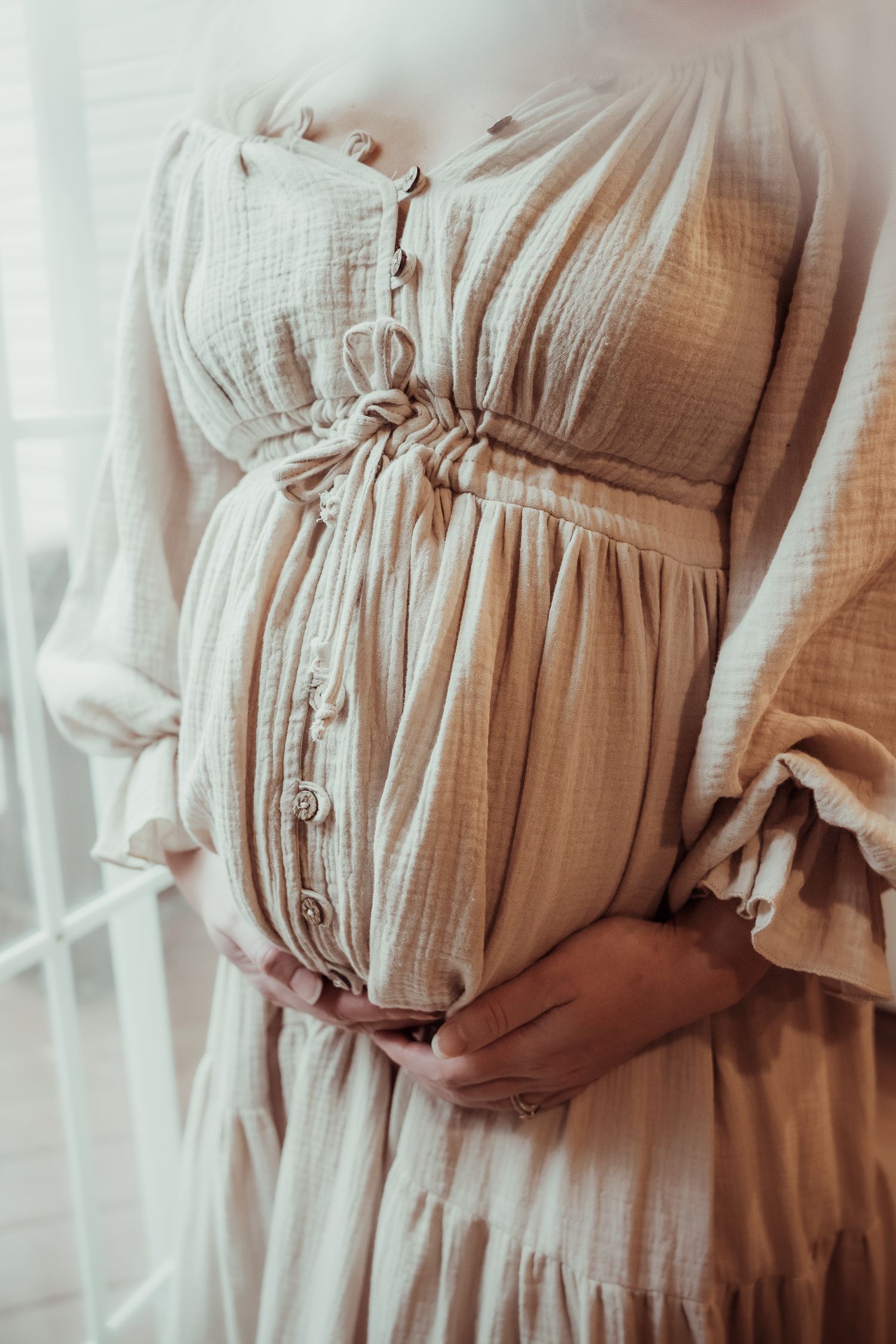 Close-up views of a beige muslin maternity dress with gathered waist detail and buttons shown from different angles.