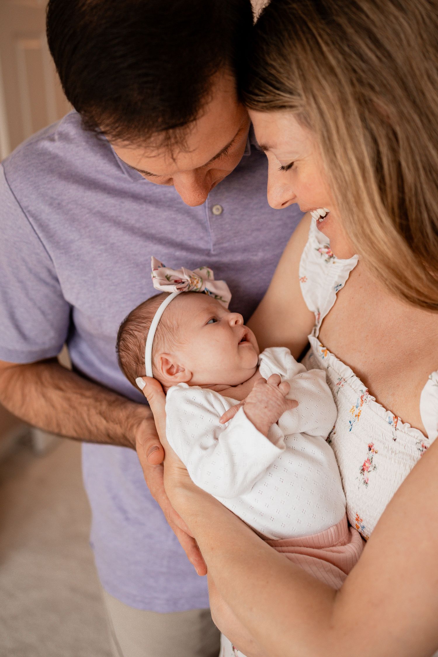 Parents sharing loving moments with their newborn baby dressed in white.