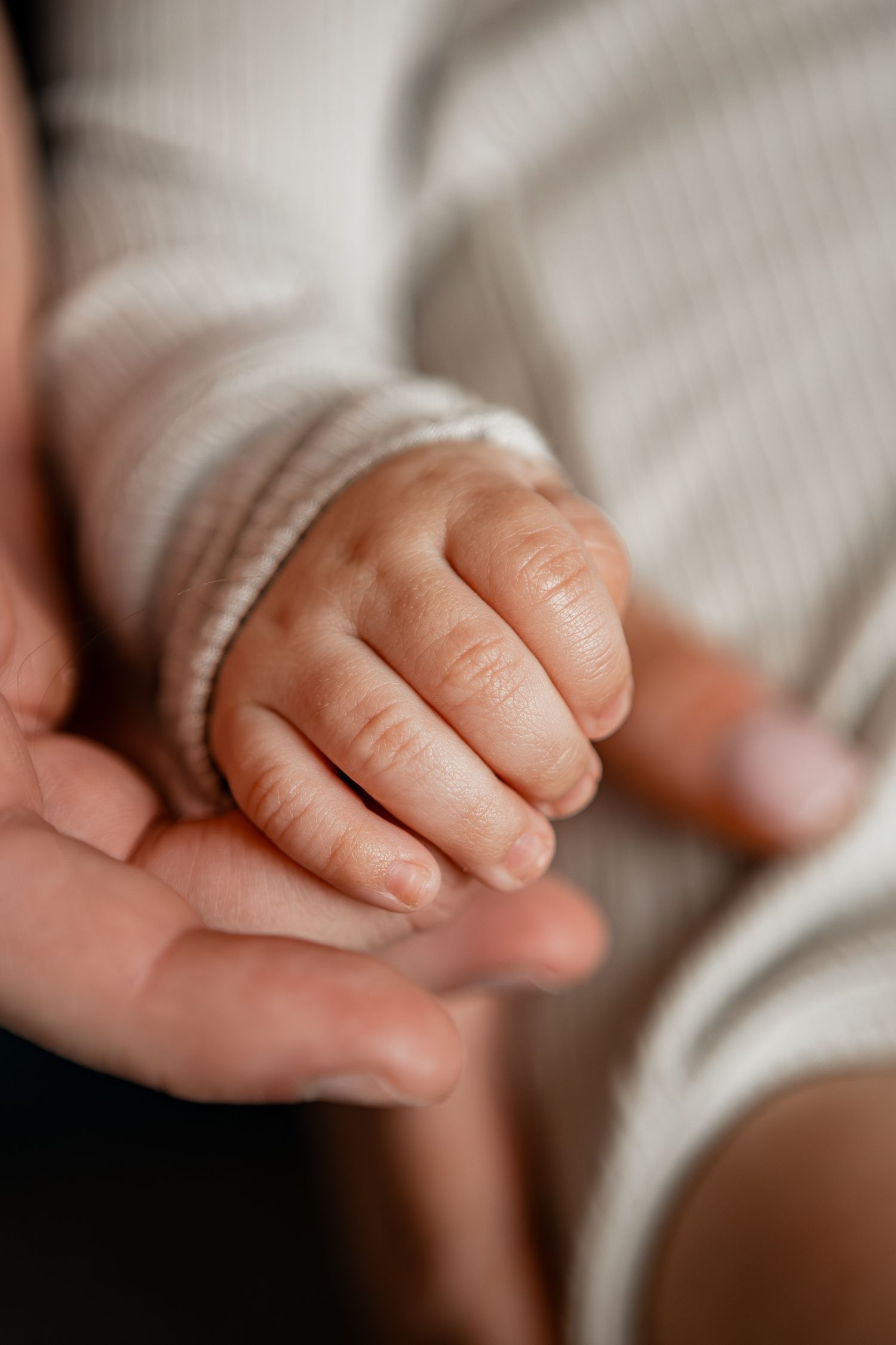 Macro close-up sequence showing tiny baby fingers on soft white fabric.