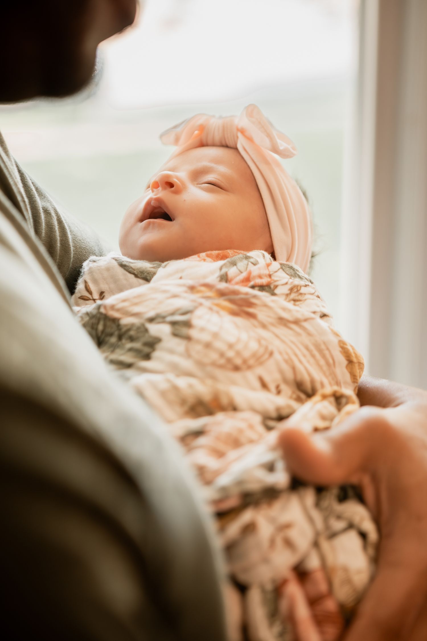 A series of images showing a baby yawning and relaxing while laying on soft beige blankets and pillows.
