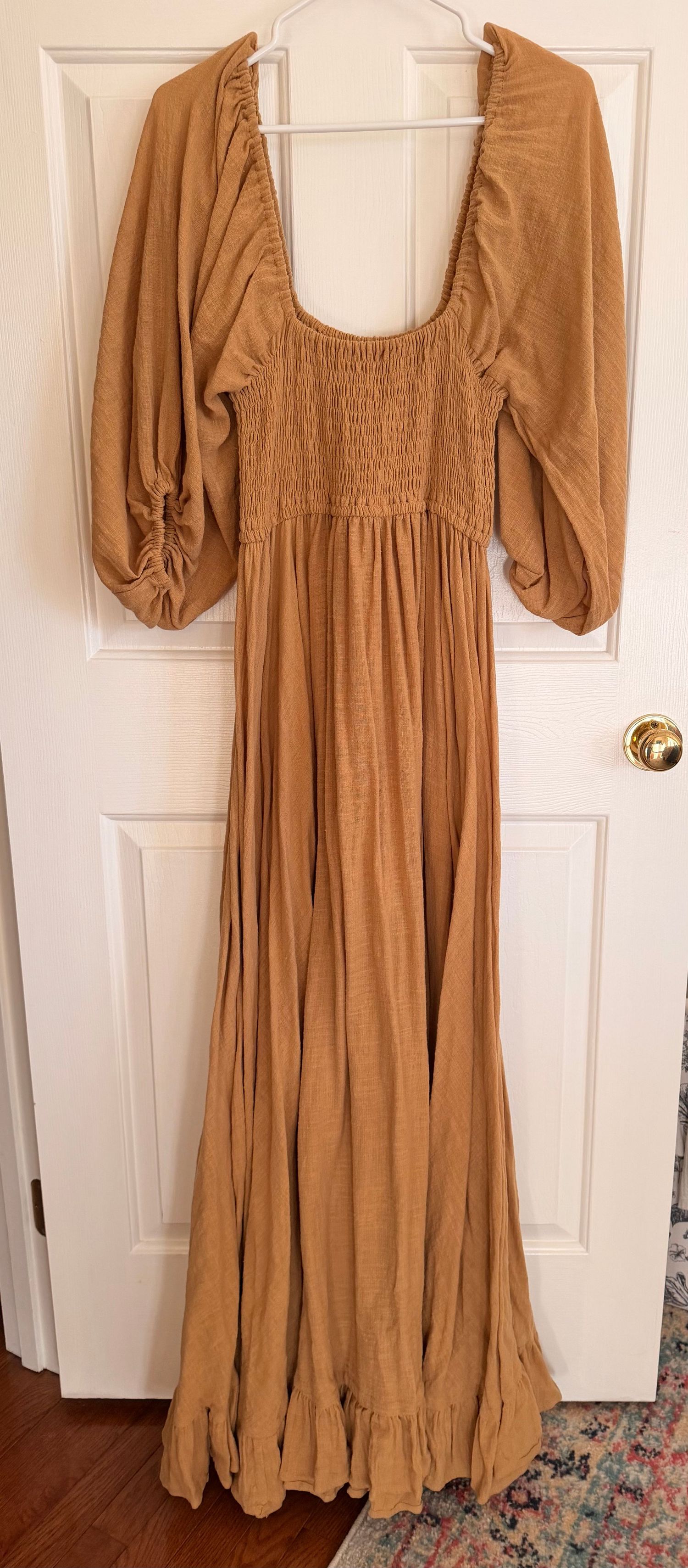 Tan babydoll dress with puff sleeves and smocked bodice shown from different angles on white door background.