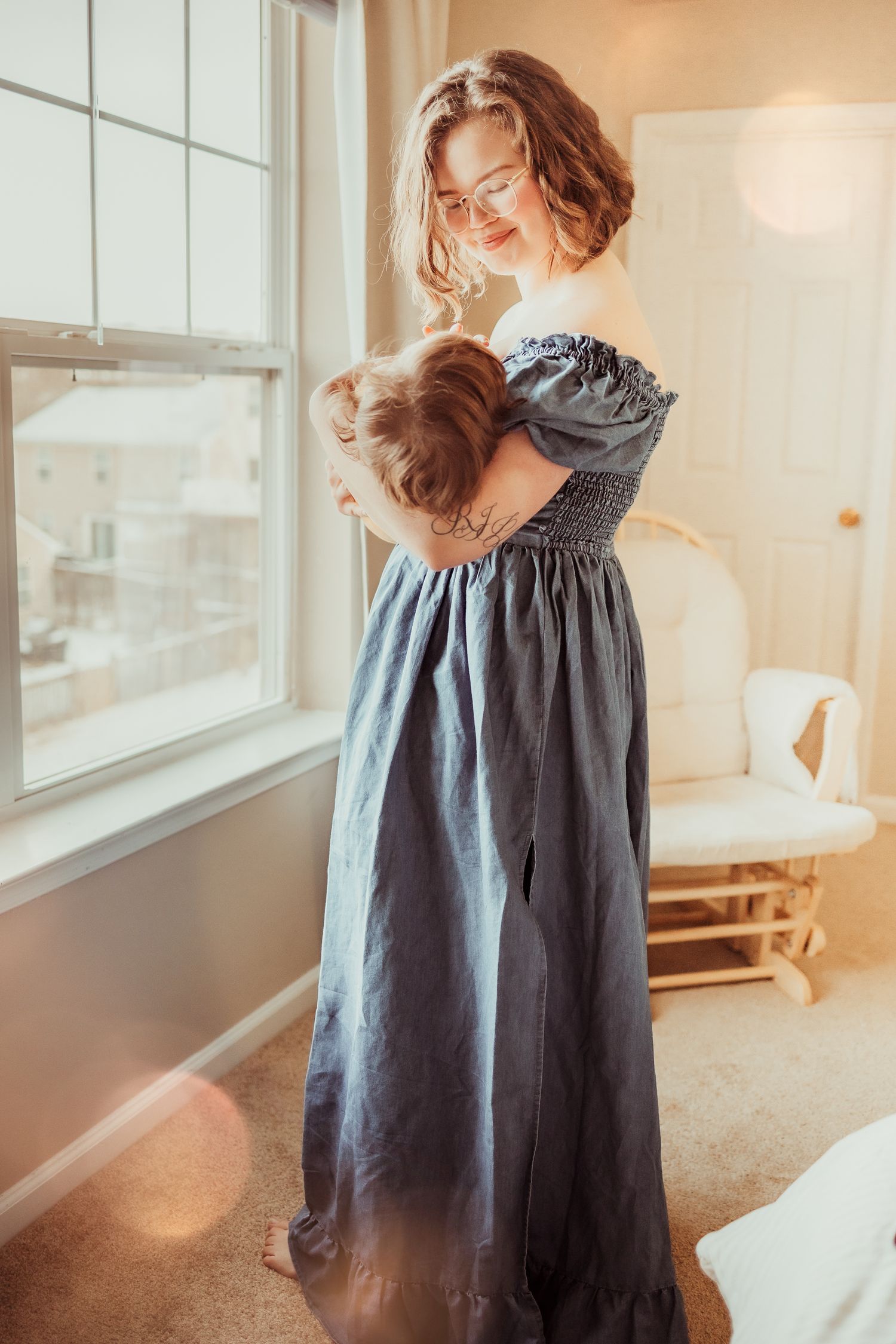 A person in a flowing gray linen dress twirls by a bright window in a sunlit room.
