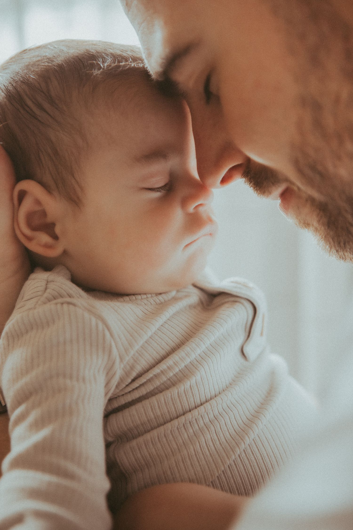 Close-up of tender family moment with baby in cream sweater.