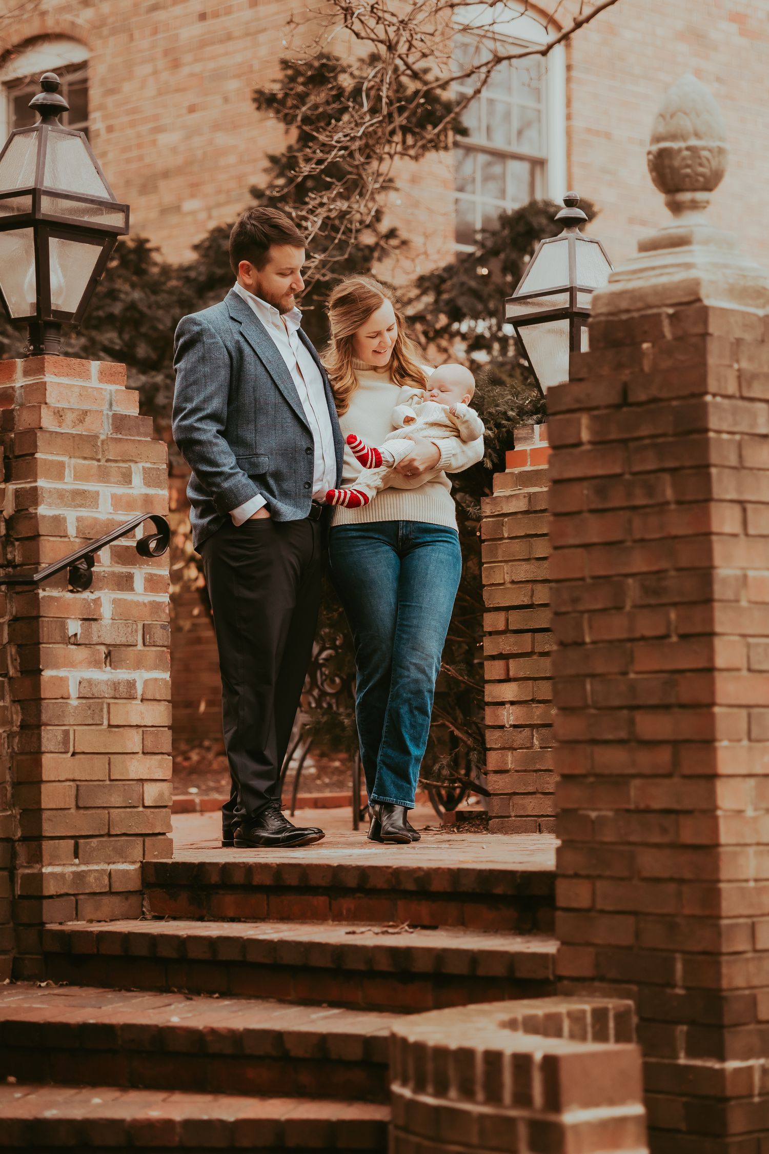 A family stands together on brick steps outside a historic building with vintage lampposts in warm autumn lighting.
