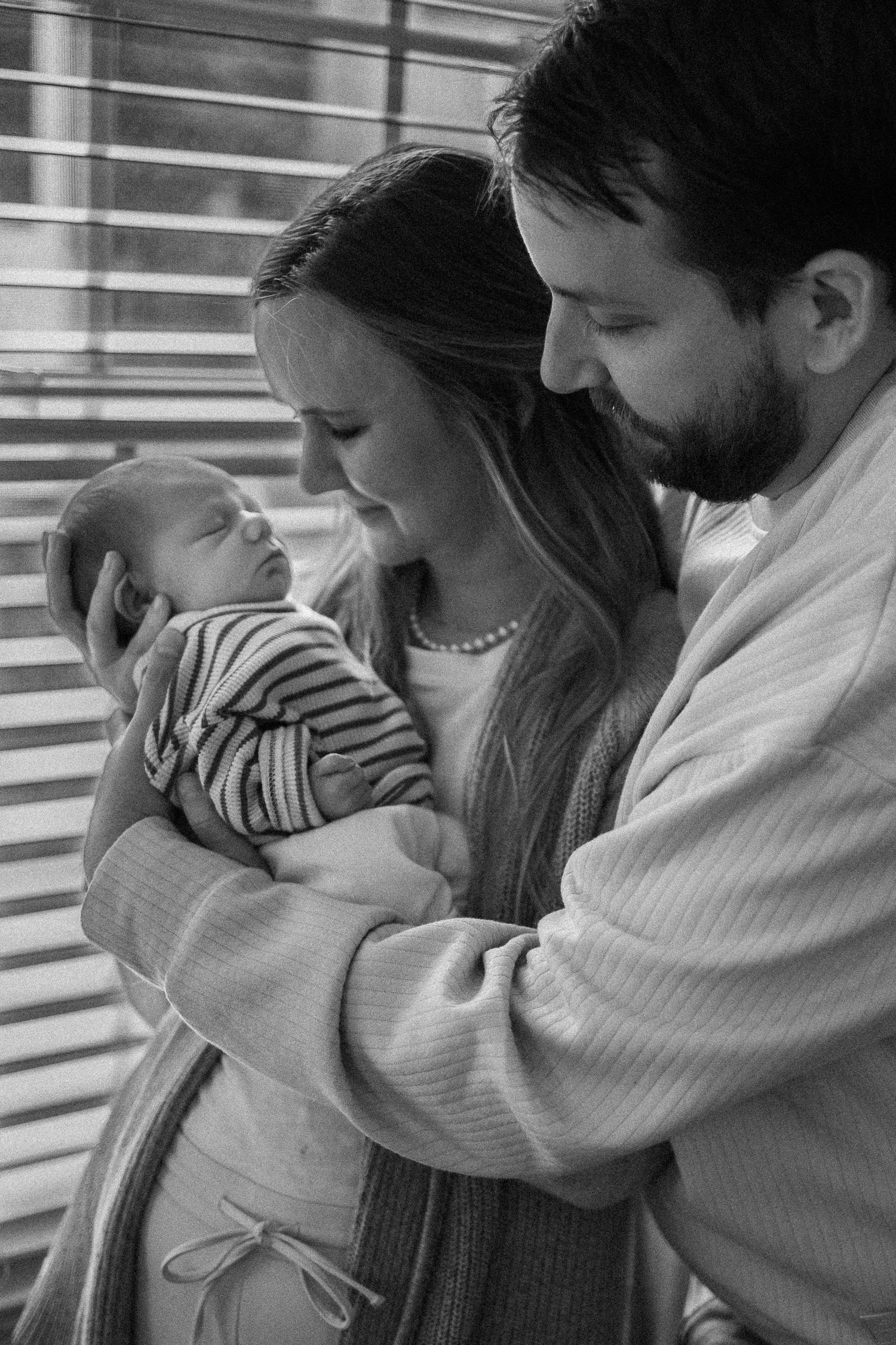 Black and white photo series showing intimate moments between parents and their newborn.