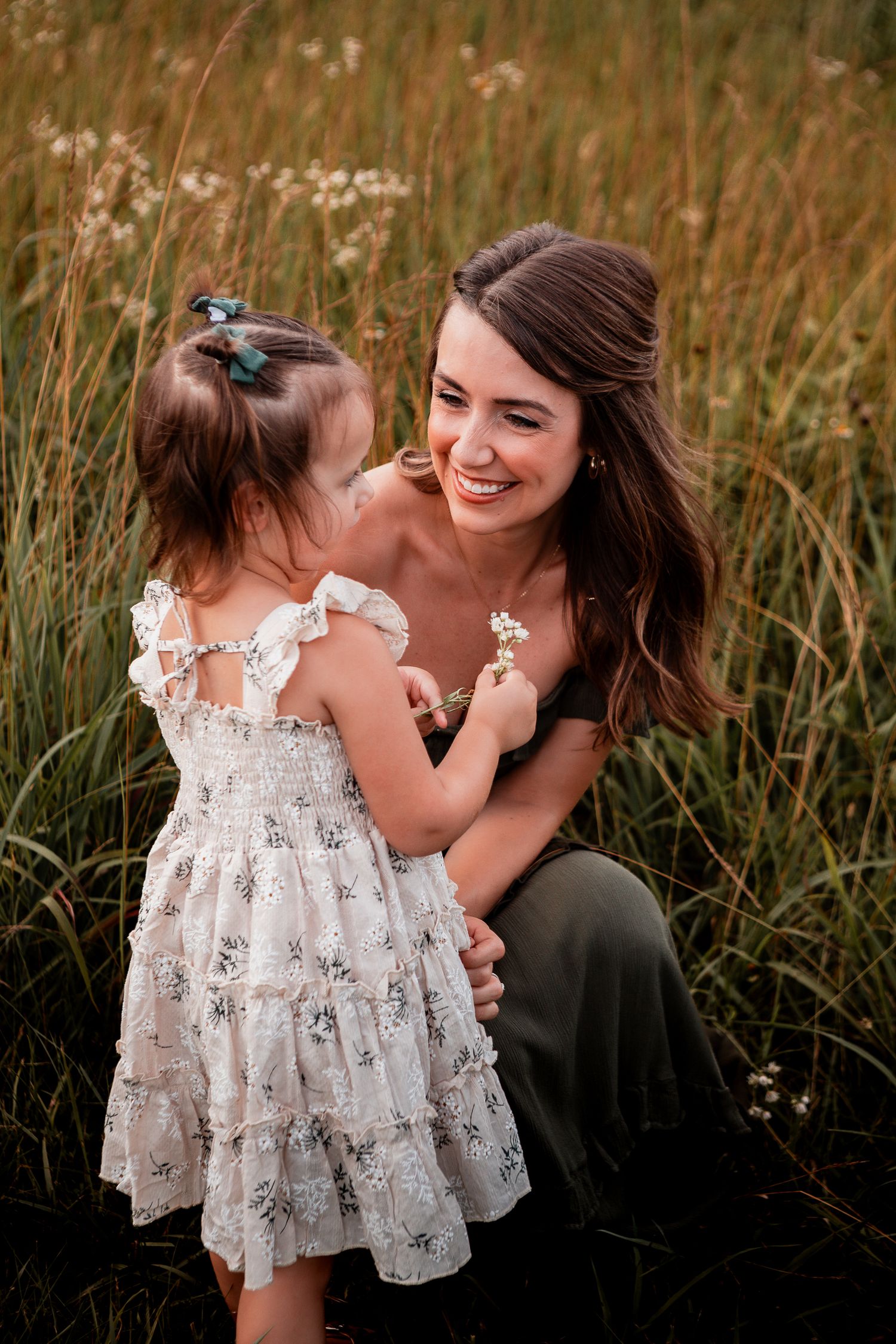 A tender moment between two people sharing laughter and joy in a field of tall golden grass at sunset.