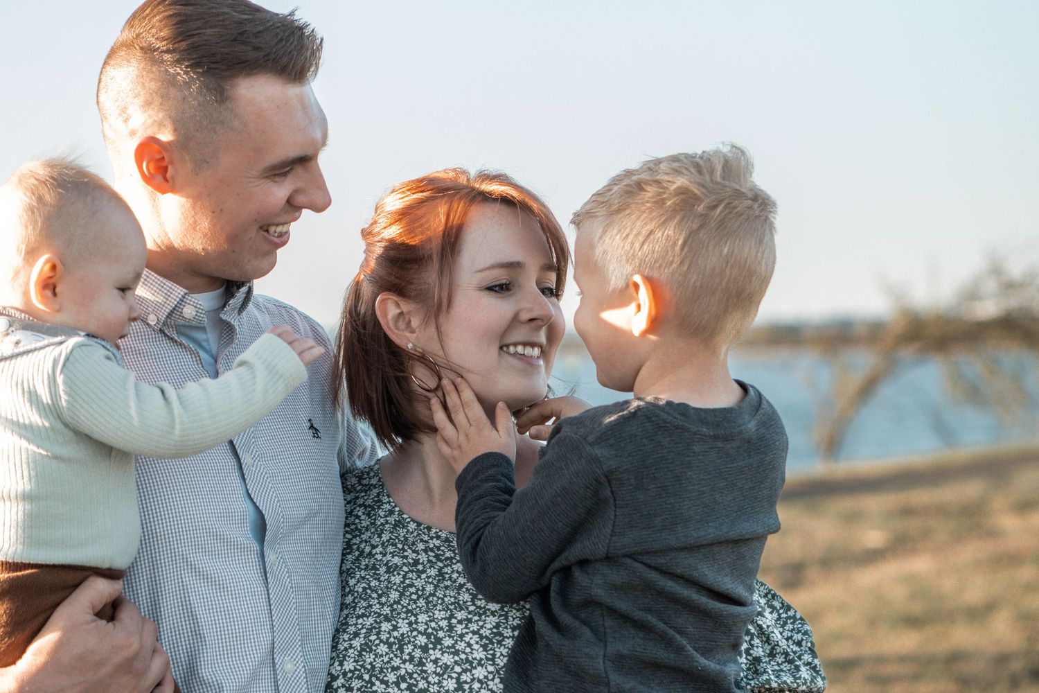 A loving family shares a joyful moment together outdoors during golden hour.