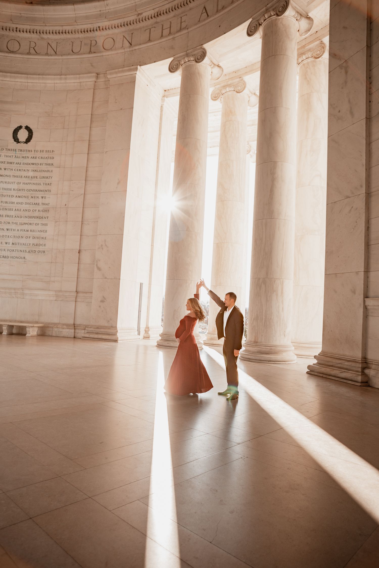 Silhouettes of people dancing in sunlit marble hallway of Jefferson Memorial creating dramatic shadows on floor.