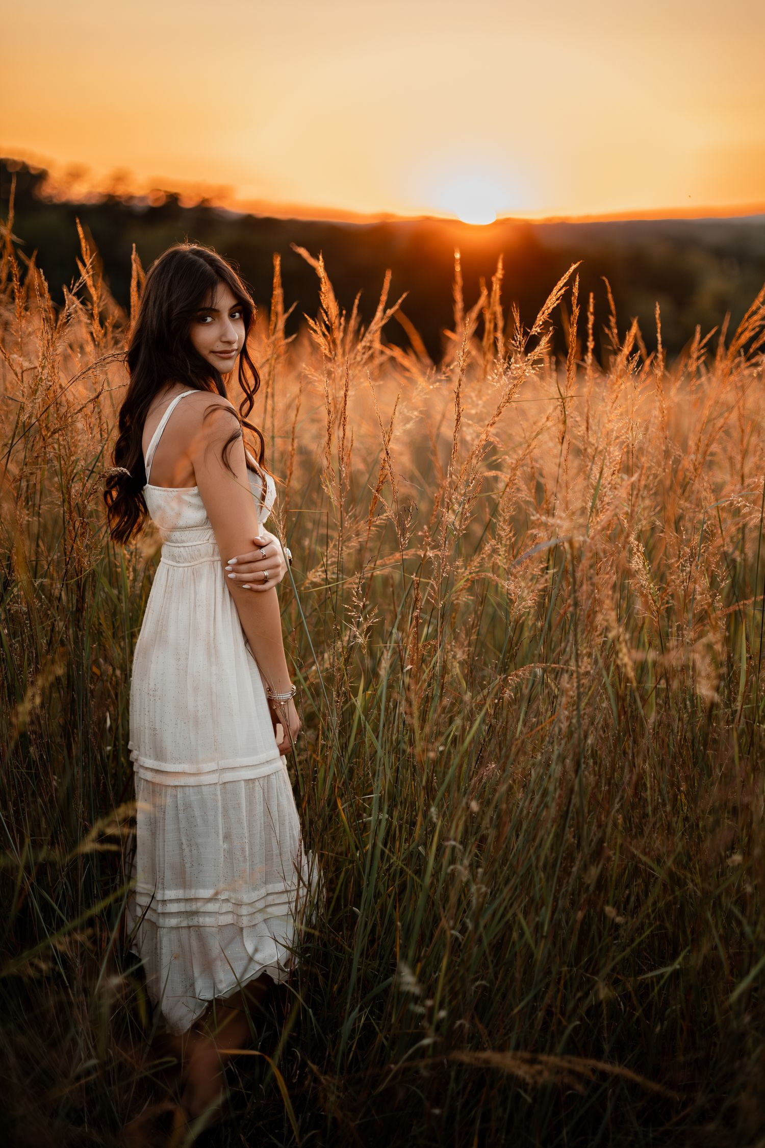 White sundress silhouette against tall grass at golden sunset in rural field.