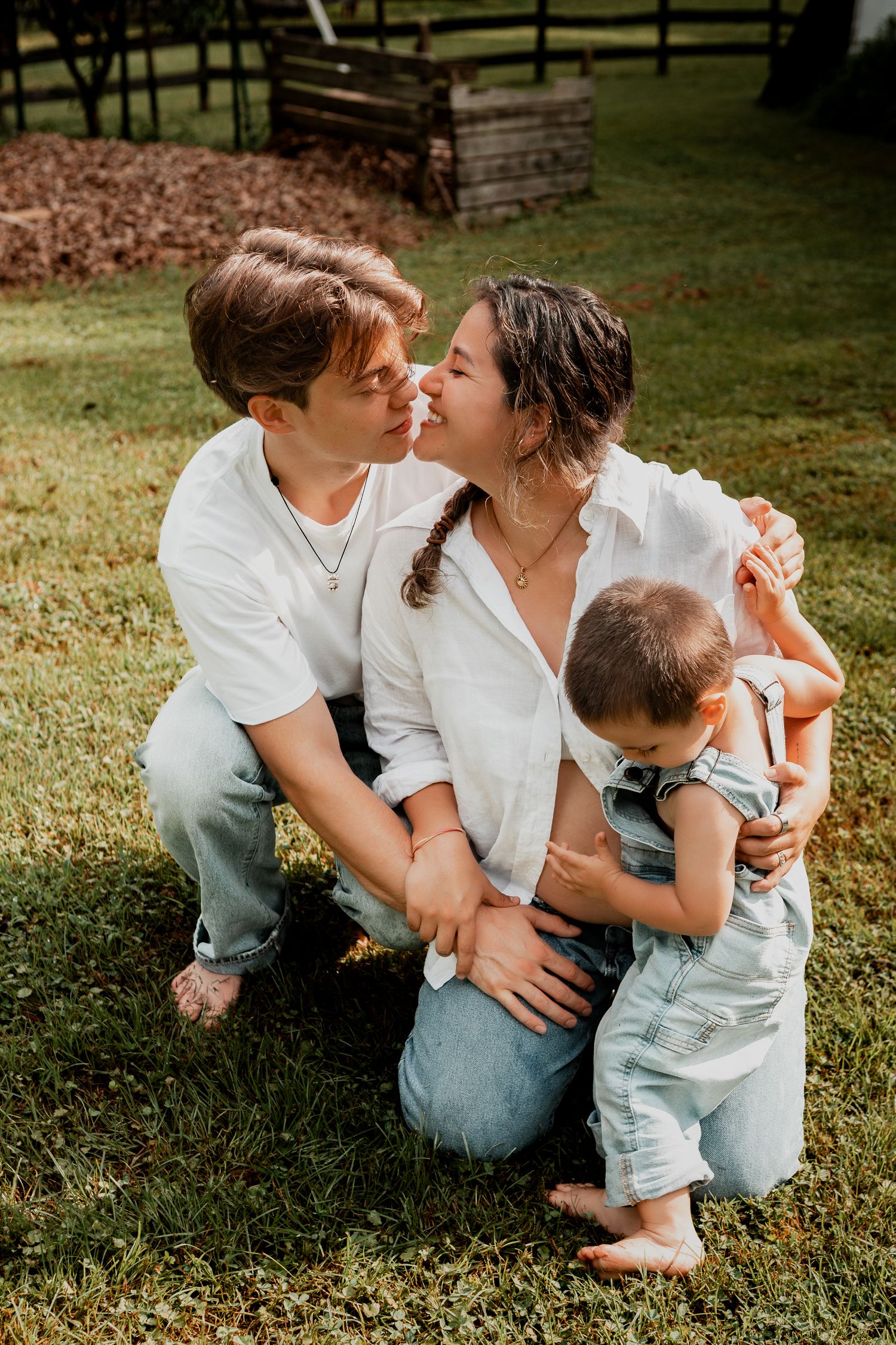 Family cuddles together on green grass during outdoor lifestyle photography session.