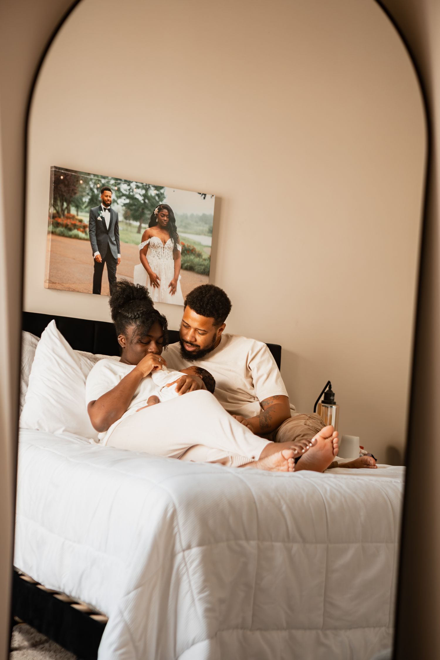 A couple shares tender moments while relaxing together on white bed linens in their bedroom.