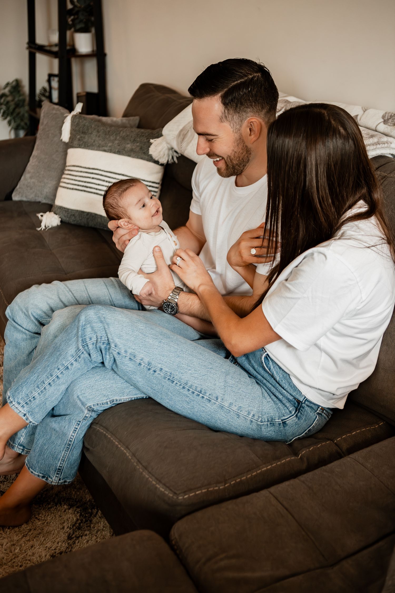Family members sharing playful moments and laughter while relaxing together on a brown couch.