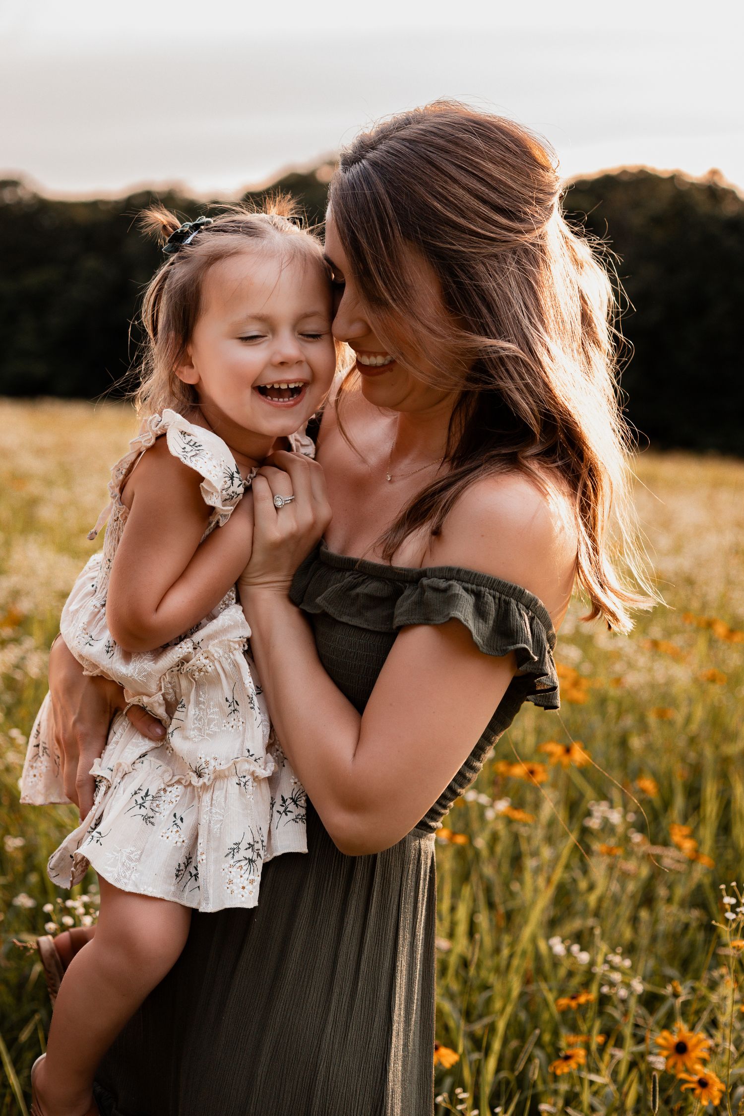 Tender family portraits in a wildflower field during sunset showing loving embraces and laughter.