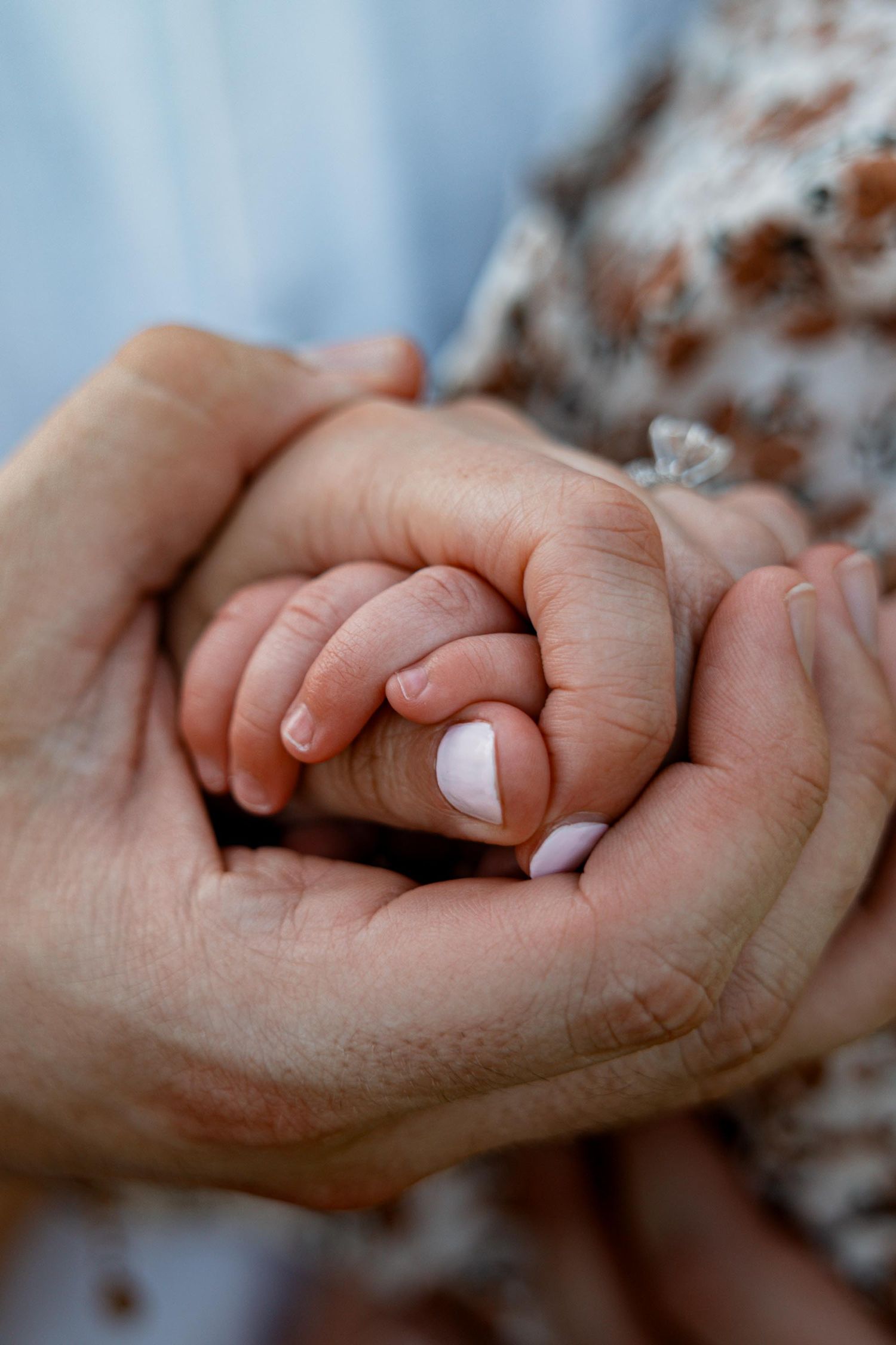 Adult hands cradling a tiny newborn baby hand, symbolizing love, protection, and the bond between parent and child.