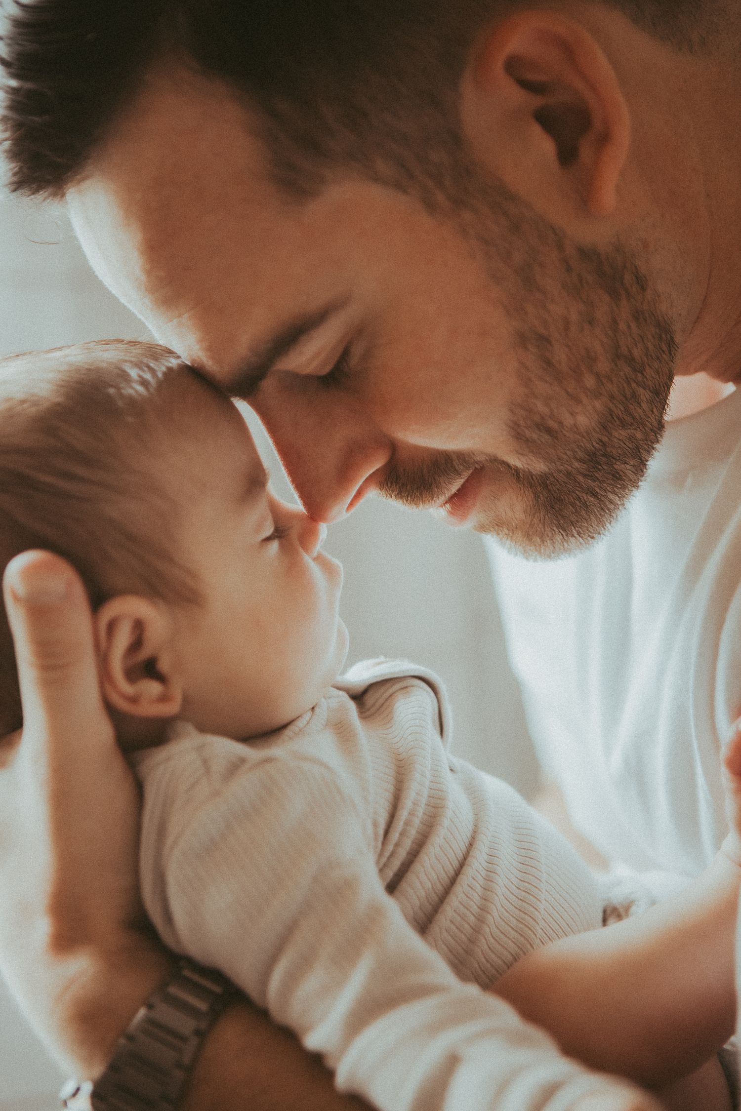A tender moment captured in warm lighting as a parent shares an intimate bonding moment with their infant.