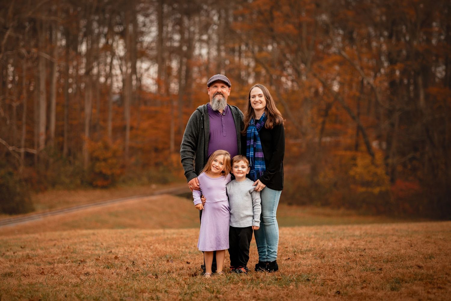 Family group portrait in autumn setting with orange and brown fall foliage.