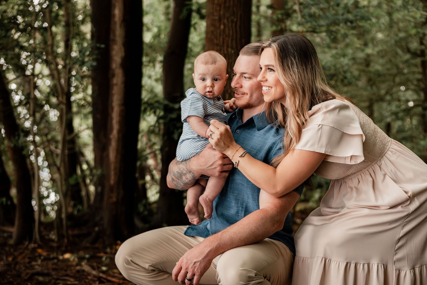 A sweet family photography session in a wooded outdoor setting shows tender moments between loved ones.
