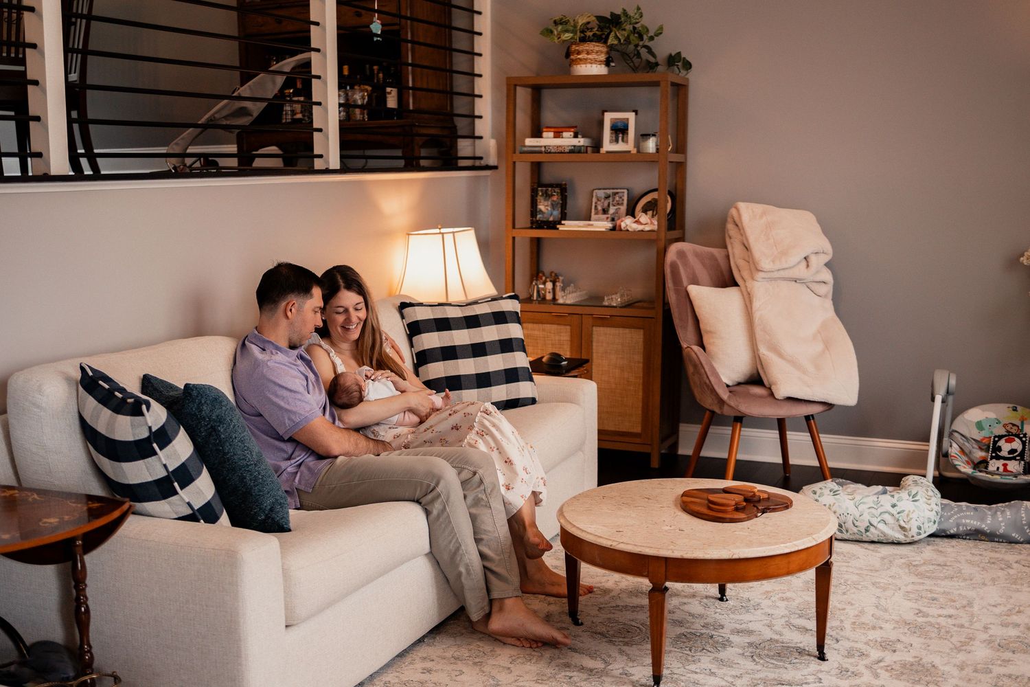 A cozy in-home lifestyle photography session showing intimate family moments on a grey couch and neutral decor.