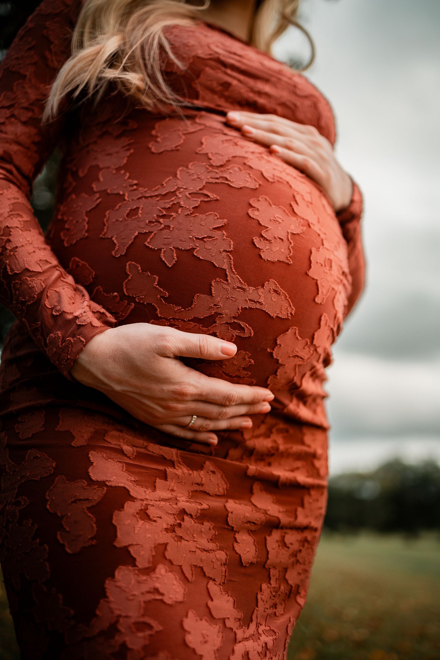 Close-up shots of a rust-colored textured maternity dress against a moody sky background.