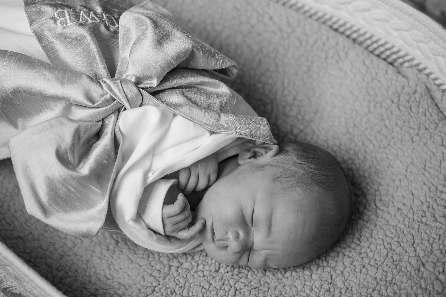 Black and white portrait of sleeping newborn wrapped in soft blanket.