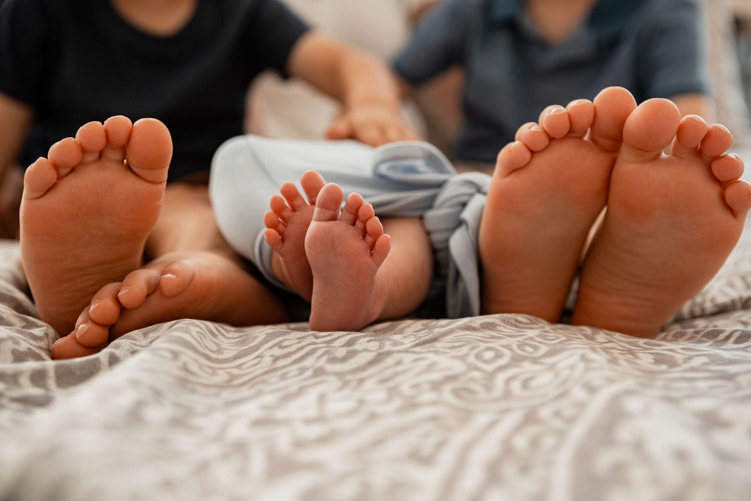 Adorable close-up of baby feet with sleepy newborn toes resting on soft white blanket or bedding.