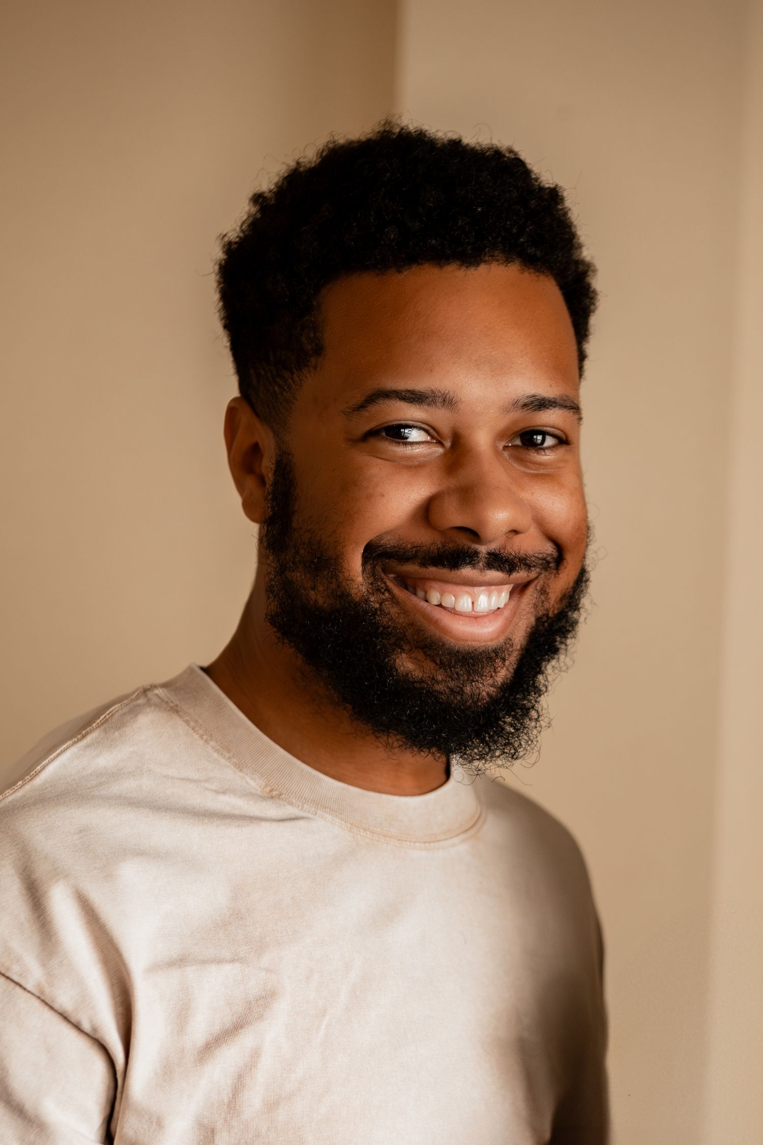 African American person wearing cream sweater smiling and posing against neutral background in multiple expressions.