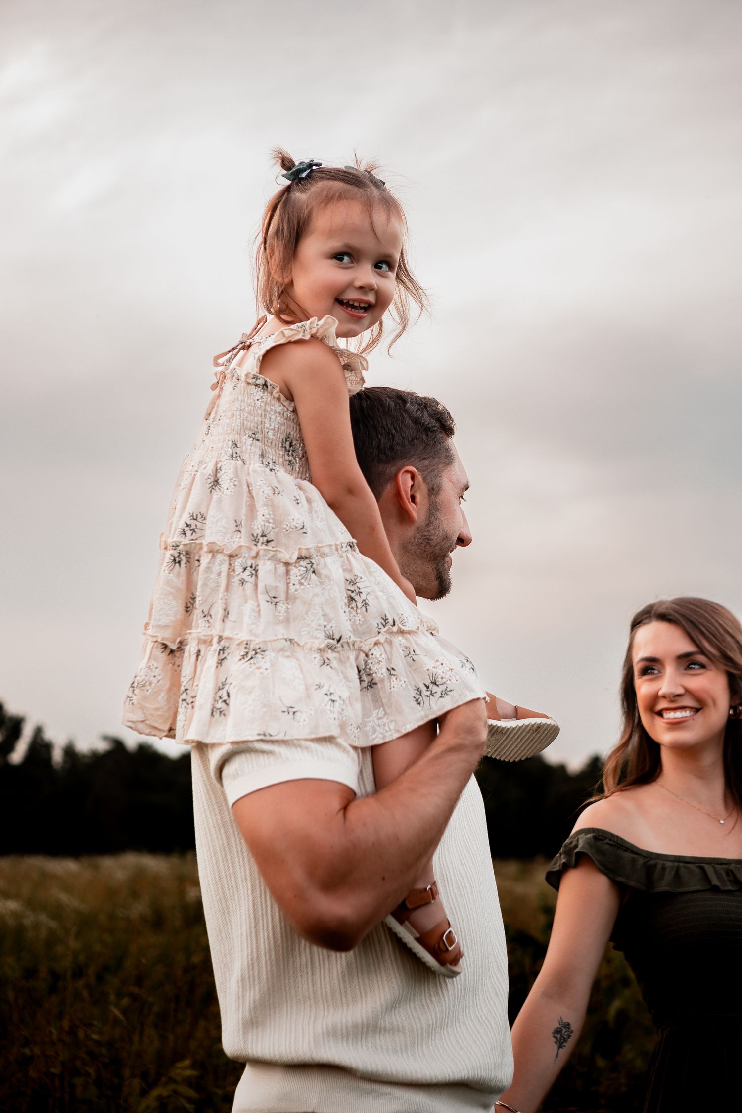 Family sharing joyful moments together in an outdoor field with moody sky at sunset.