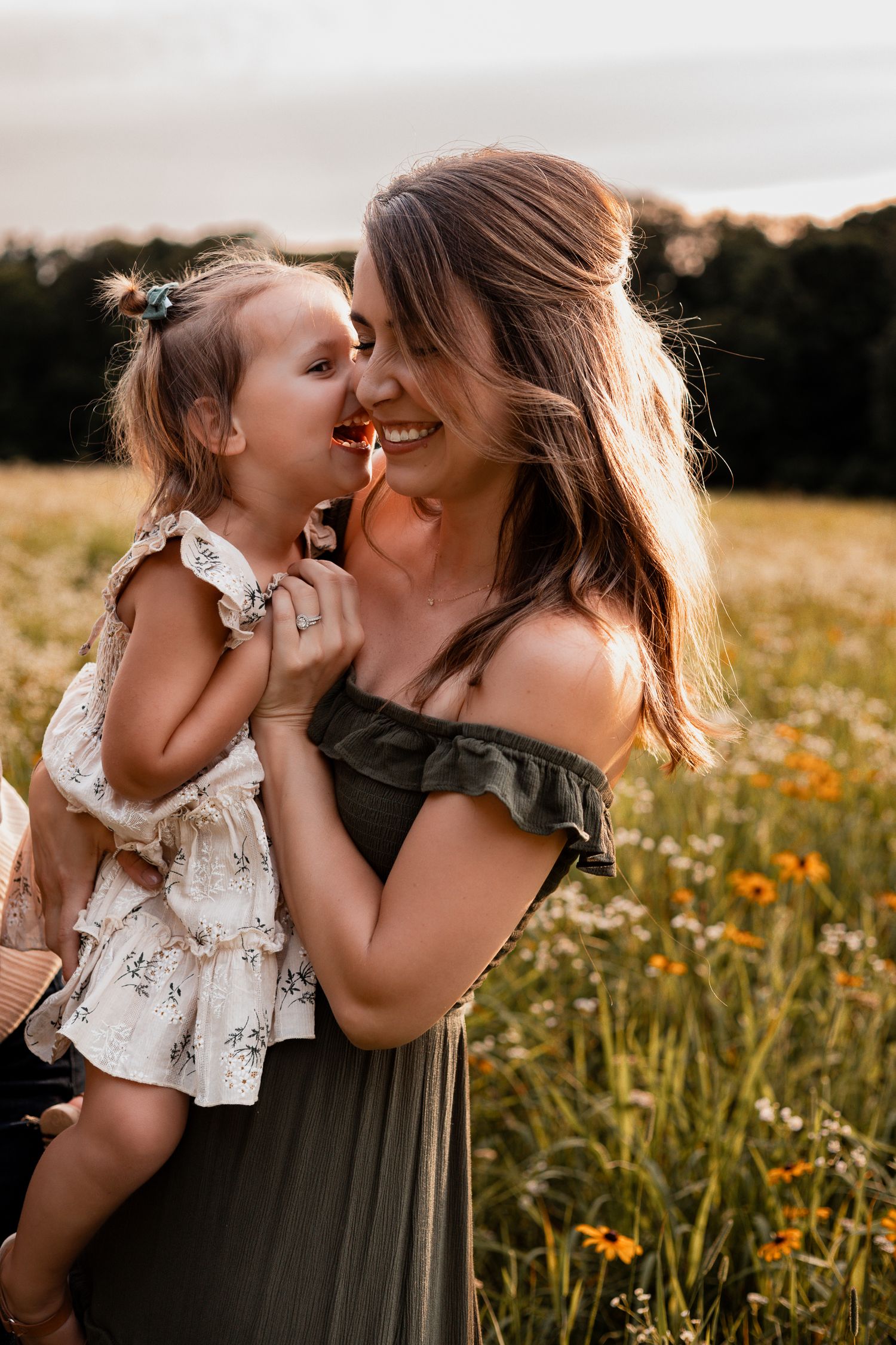 A tender moment between parent and child in a sunlit wildflower meadow at golden hour.